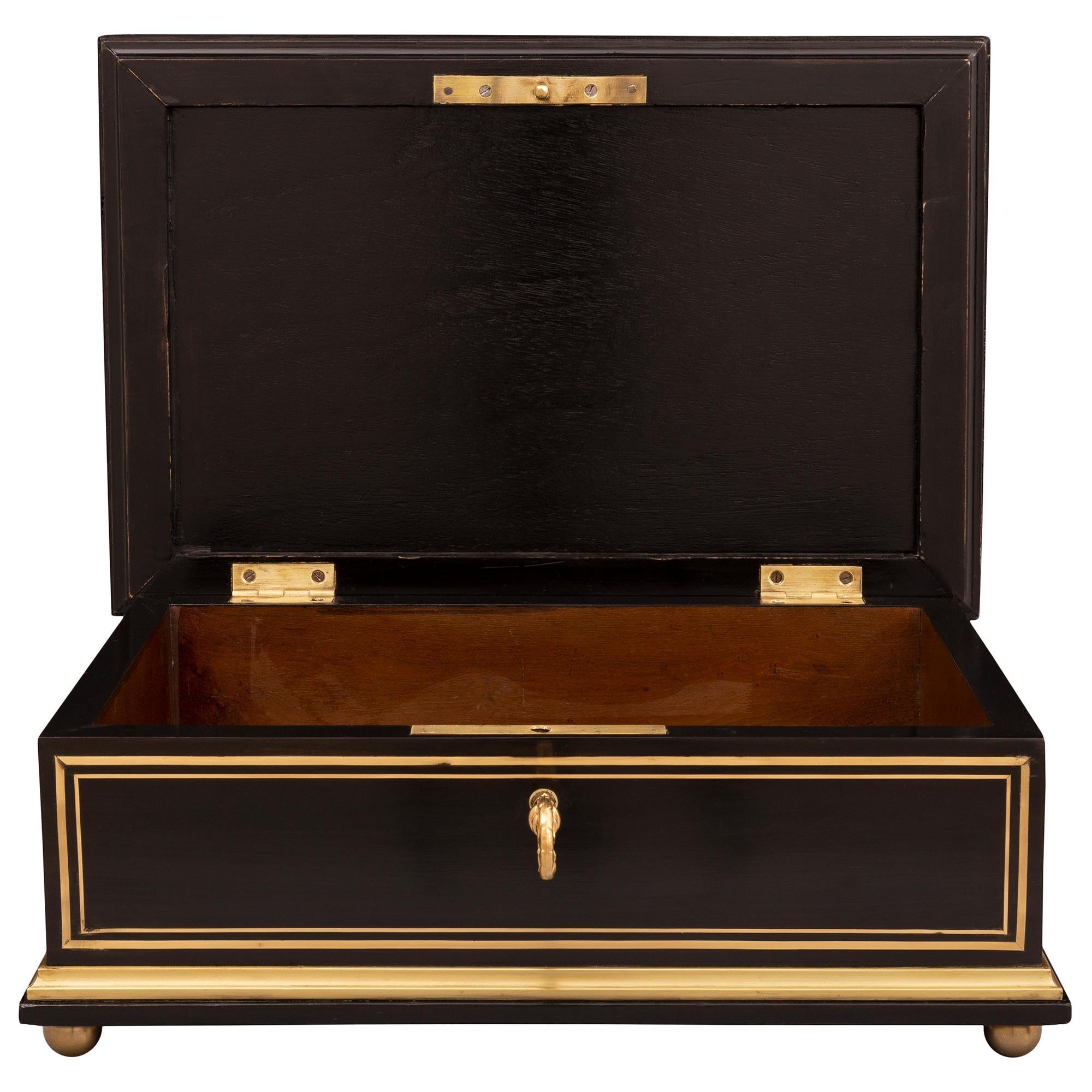 A most elegant French 19th century Napoleon III period ebony, ormolu, and brass box. The box is raised by fine ormolu ball feet below a lovely wrap around mottled band. Each ebony side is framed within exceptional brass fillets while the front