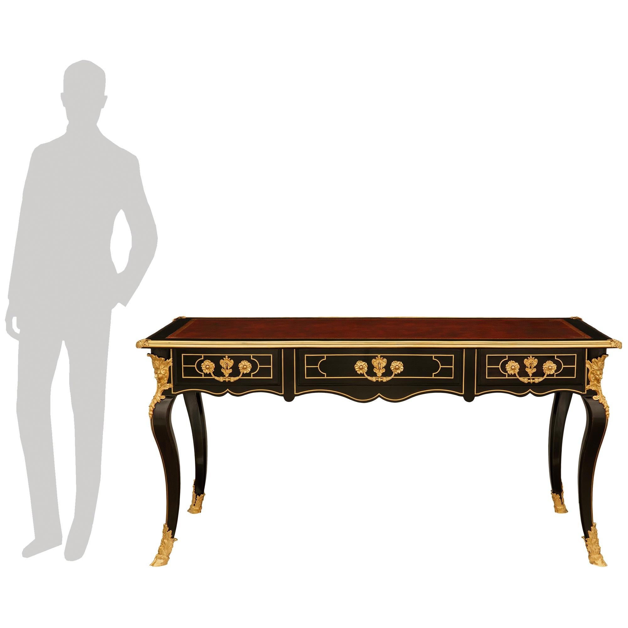 Una magnifica scrivania francese di alta qualità del XIX secolo del periodo Regence di Napoleone III, in legno di frutta ebanizzato, pelle e boulle di ormeggio. Questa splendida scrivania a tre cassetti è sollevata da quattro gambe cabriole con