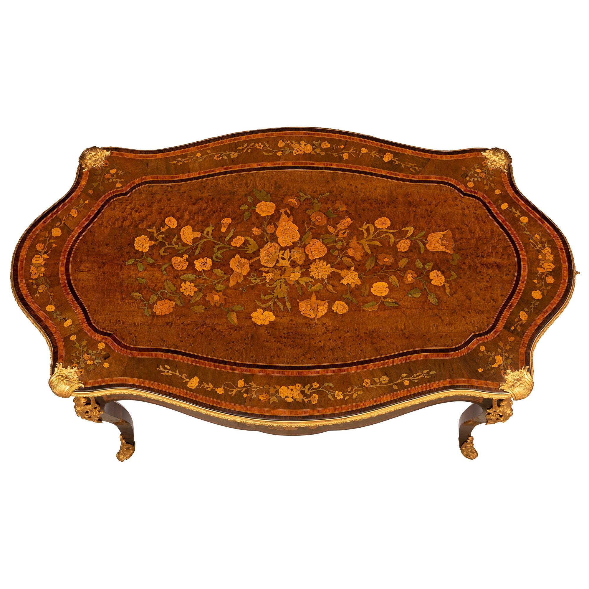 Superbe table de centre en bois exotique et bronze doré, d'époque Louis XV et Napoléon III, datant du milieu du XIXe siècle. La table à deux tiroirs en forme de feston est surélevée par d'élégants pieds cabriole en palissandre avec des sabots
