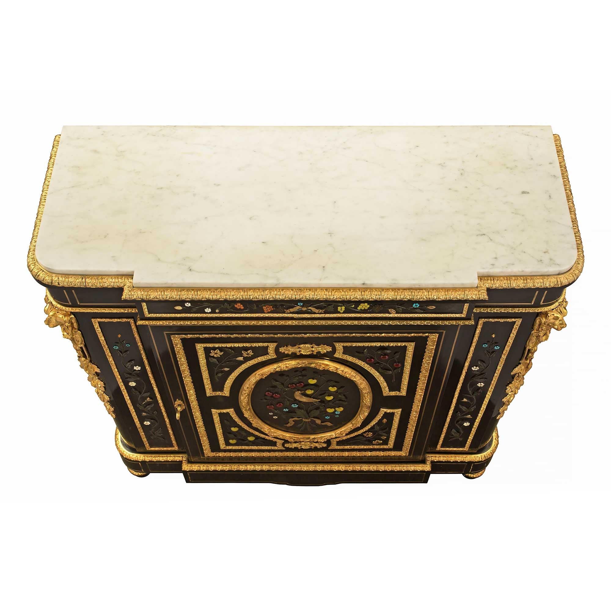 A sensational French 19th century Napoleon III period ebony, brass, ormolu, semi precious stone and marble cabinet. The cabinet is raised by mottled topie shaped feet with a fine wrap around ormolu band. The bottom frieze displays a most elegant
