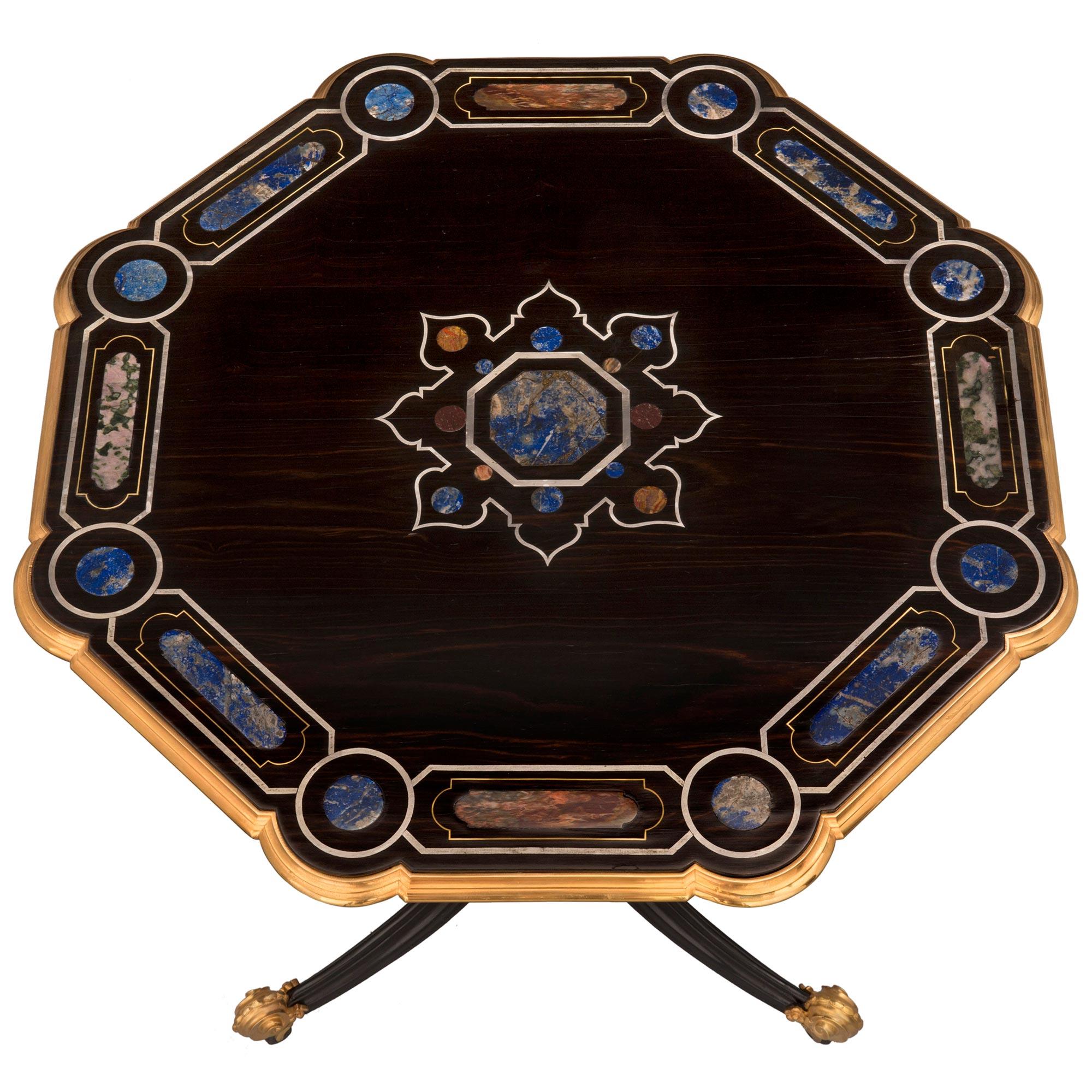 Magnifique table d'appoint d'époque Napoléon III du XIXe siècle, en ébène, laiton, bronze doré et incrustations de pierres semi-précieuses. La table est surélevée par une base tripode avec d'élégants pieds en bronze doré à volutes avec leurs