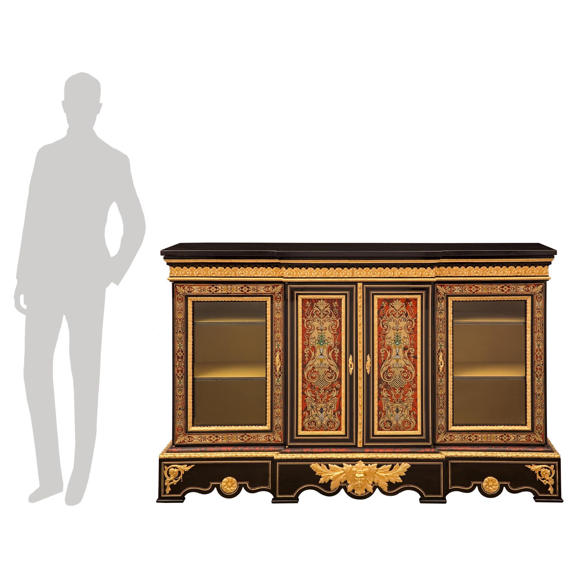 Un étonnant et unique cabinet vitrine d'époque Napoléon III du 19ème siècle en ébène, bronze doré, écaille de tortue, laiton, étain, Lapis Lazuli, nacre et marbre noir belge, signé Pretot. Le buffet à quatre portes est surélevé par une belle base de