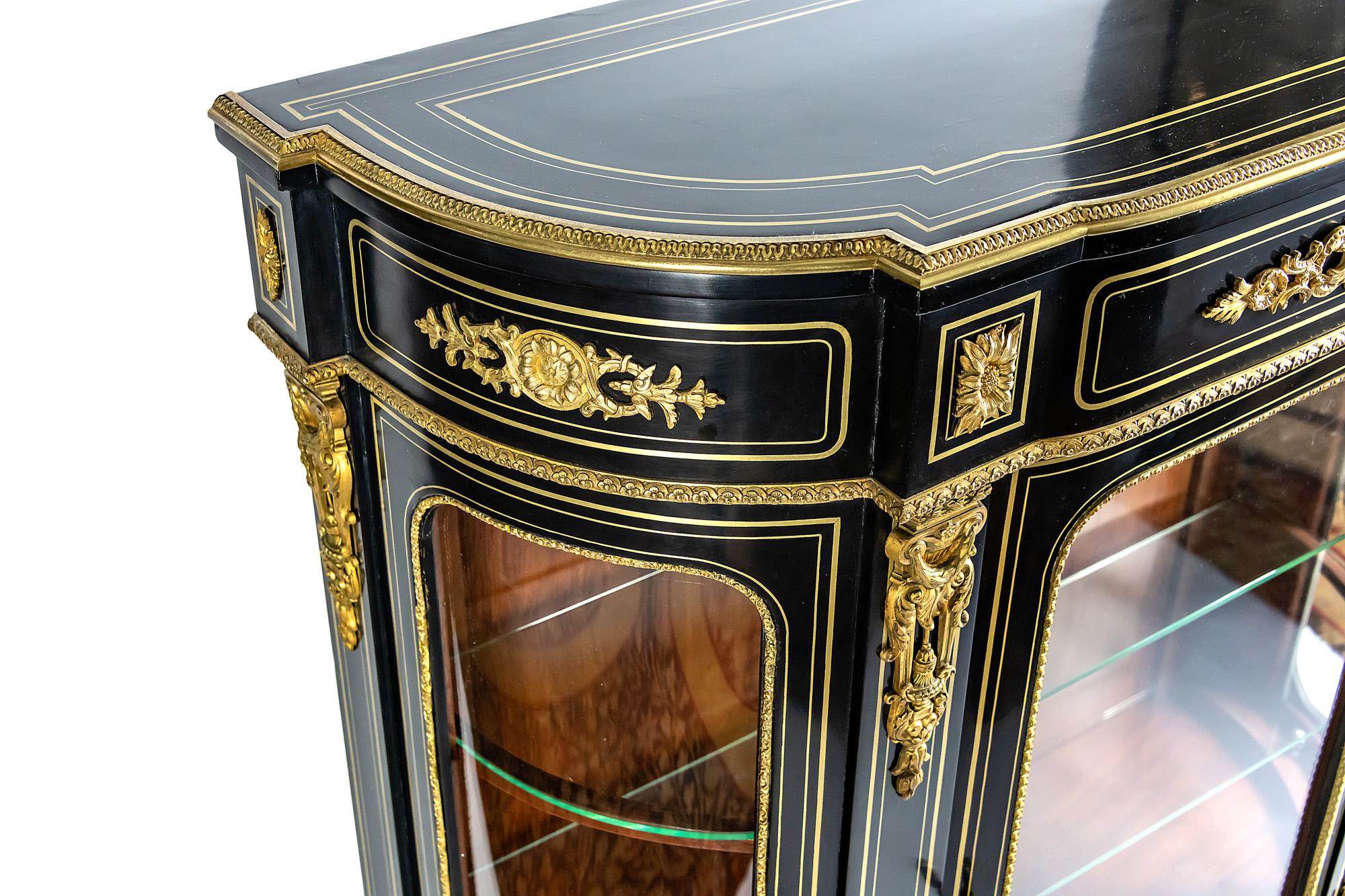 French antique Napoleon III vitrine cabinet is after renovation. Wood is decorated with inlaid brass and bronze details. Inside there are two glass shelves. Side parts are with perfect curved glass.