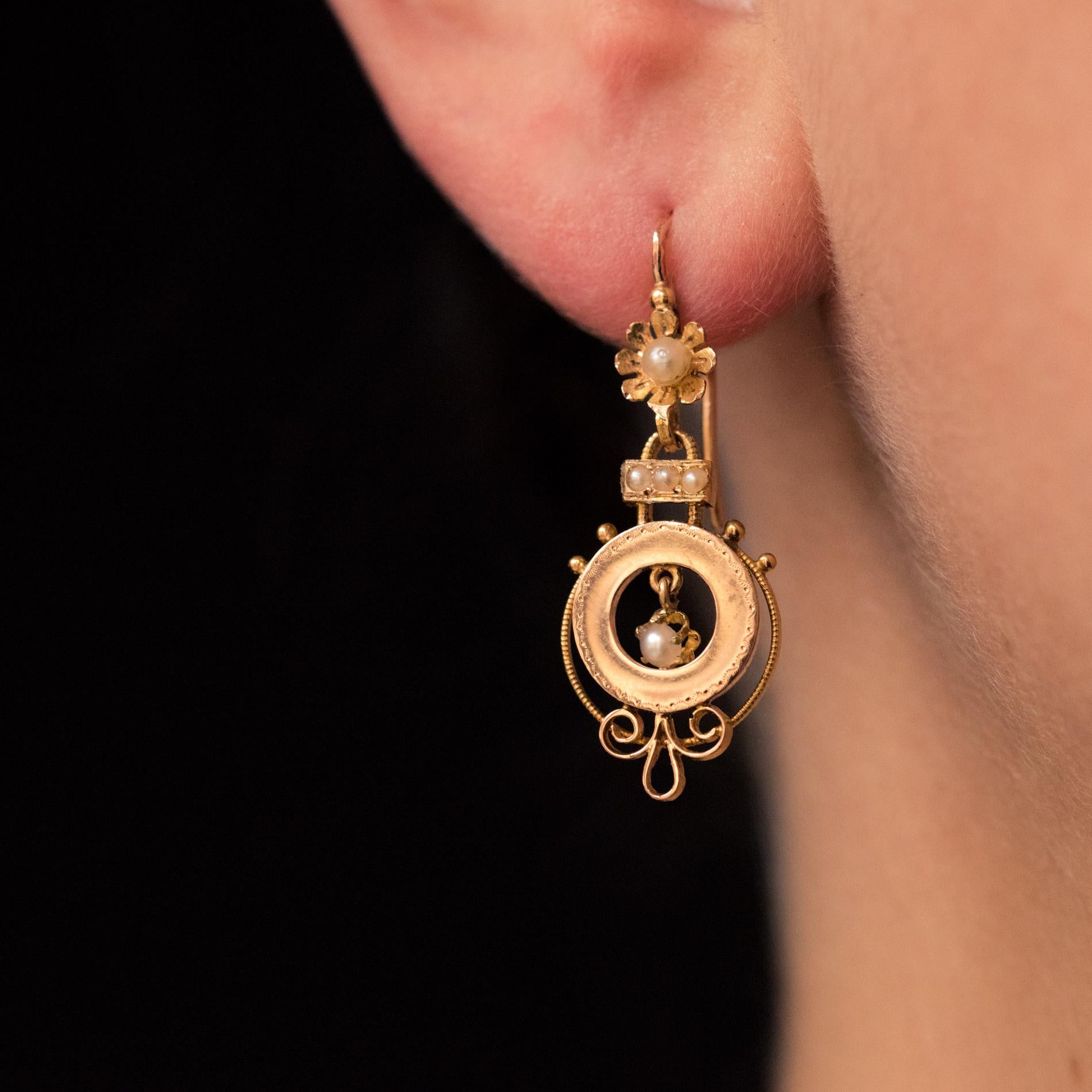 For pierced ears.
Earrings in 18 karat rose gold, eagle's head hallmark.
Pair of ear pendants, each one consists of a lever- back earring representing a daisy whose heart is a natural pearl. It retains a circular motif as a pendant with a chiseled