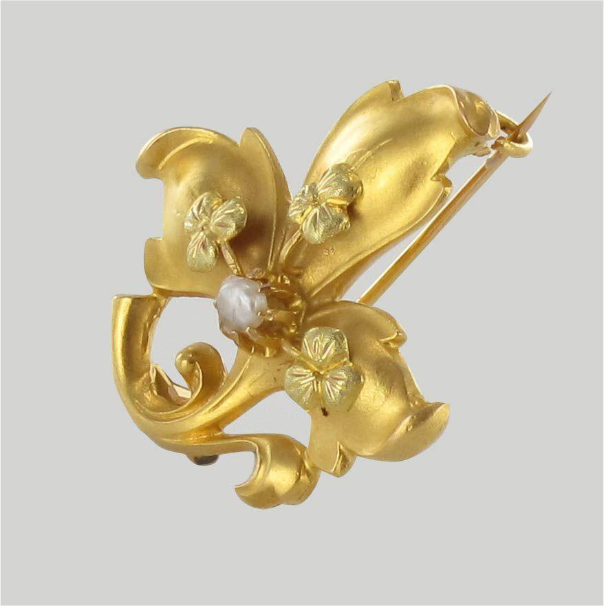 Brooch in 18 karat yellow gold, horse's head hallmark.
Lovely antique brooch, it represents a lily flower in satin yellow gold. On each petal, there is a clover with 3 chiselled leaves and in the center a natural half-pearl set with claws. The clasp