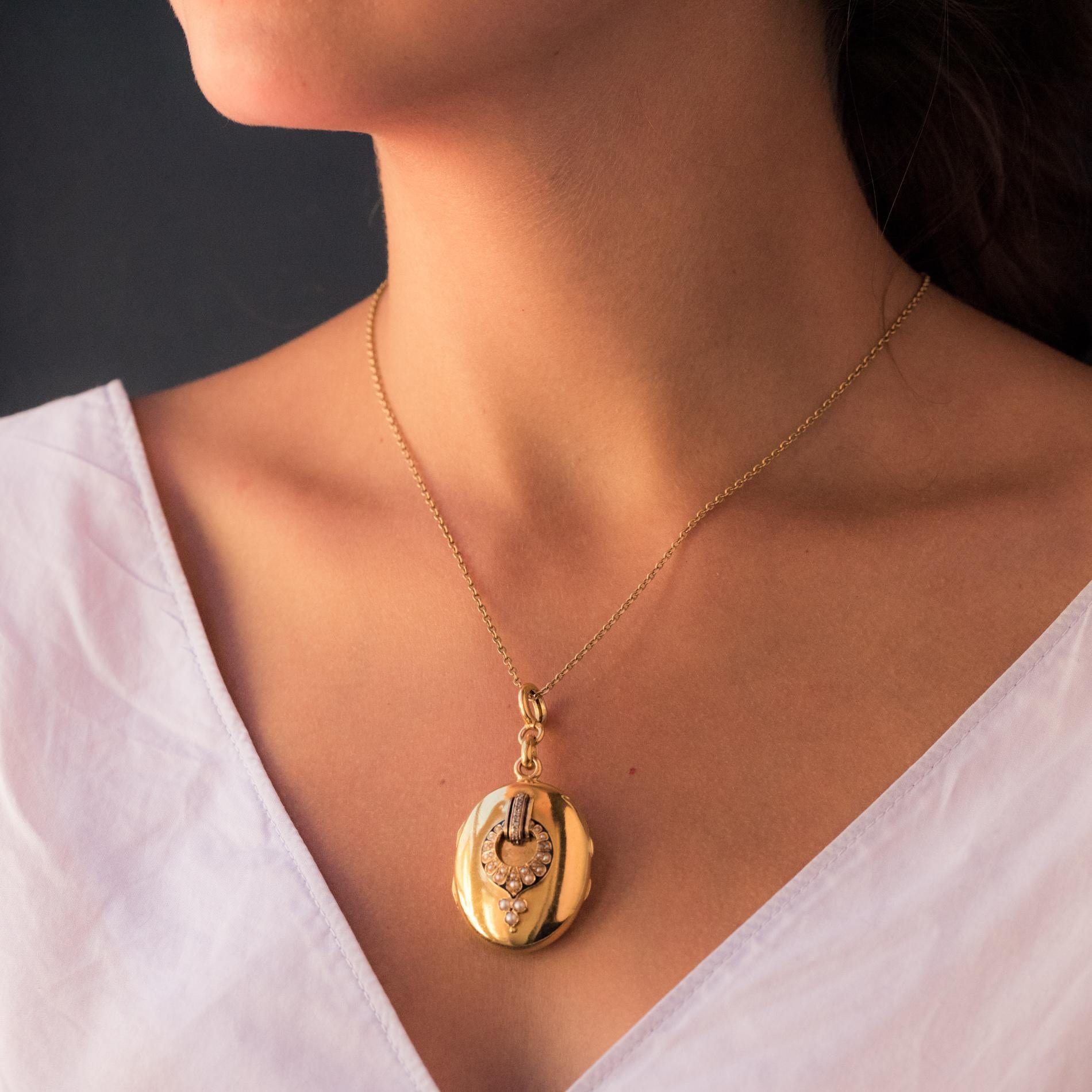 Medallion in 18 karat yellow gold, eagle's head hallmark.
Important antique oval shaped pendant, it is applied on its front face with a black enamelled motif set with half-natural pearls and a line of rose-cut diamonds. The back is smooth. It opens