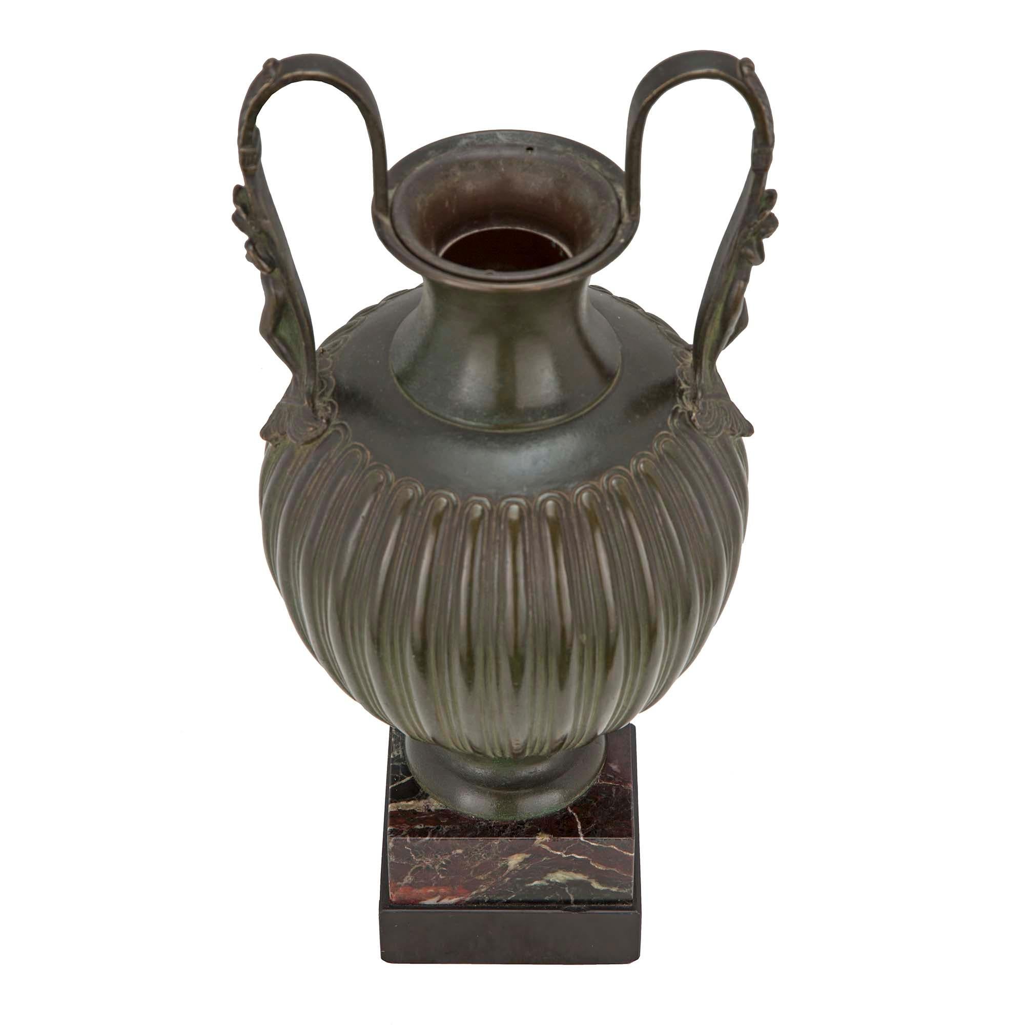 A very handsome French 19th century neo-classical patinated verdigris bronze urn. The urn is raised on a square marble base. The handsome patinated verdigris bronze urn has a reeded baluster shape. At each side are elegant handles with acanthus leaf