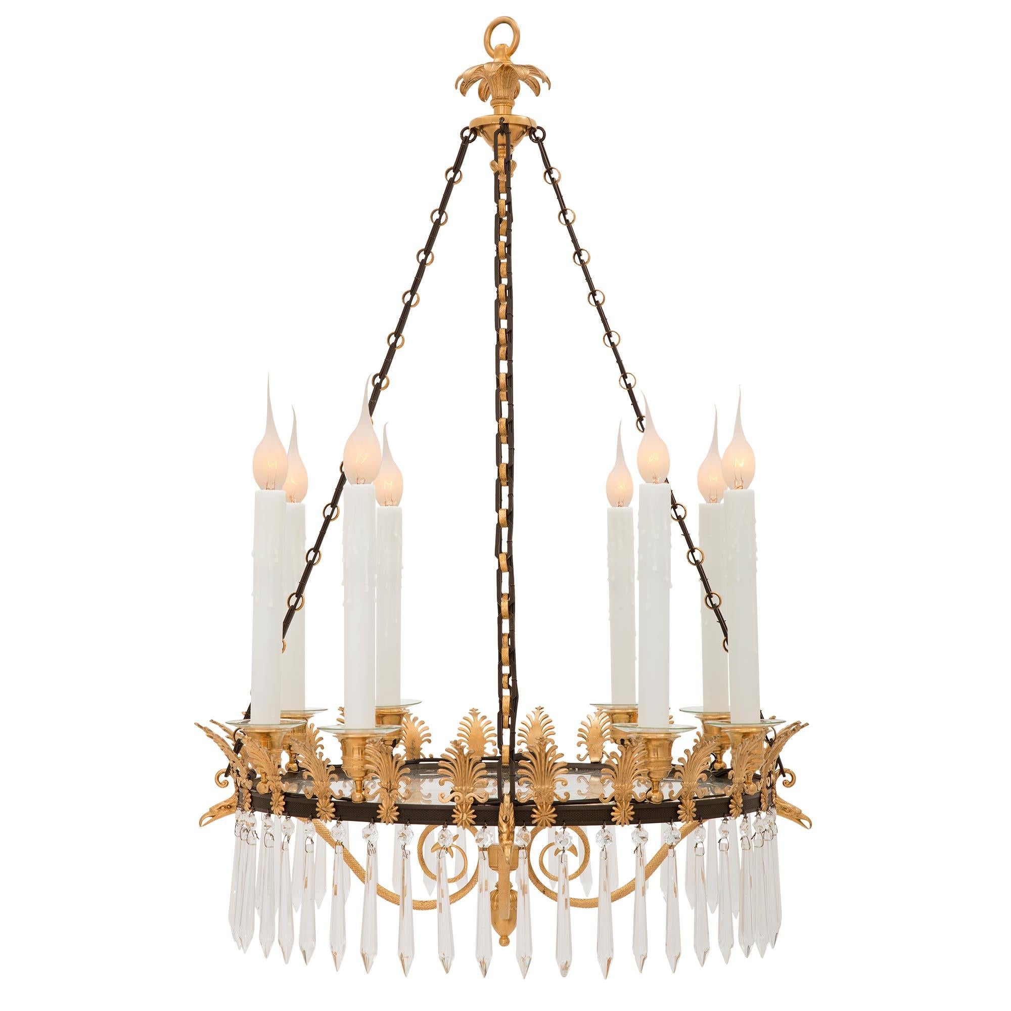 A stunning and very unique French 19th century neo-classical st. patinated bronze, ormolu, and Baccarat crystal chandelier. The eight arm chandelier is centered by a lovely bottom flower bud finial below beautiful scrolled ormolu movements with