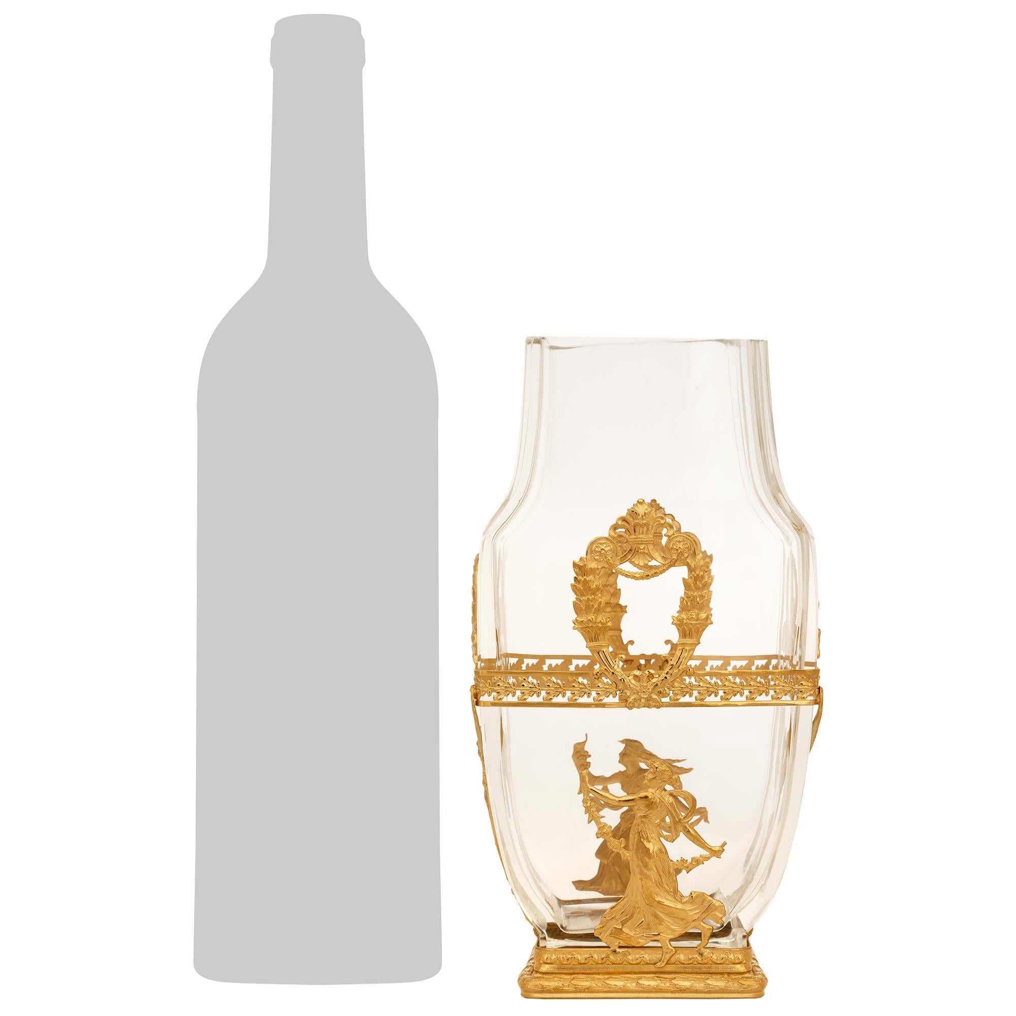 An elegant French 19th century Neo-Classical st. Crystal and Ormolu vase. This stunning baluster shaped vase displays a rectangular base decorated with berried laurel and Rais de Coeur bands. On the front and back are classically dressed female