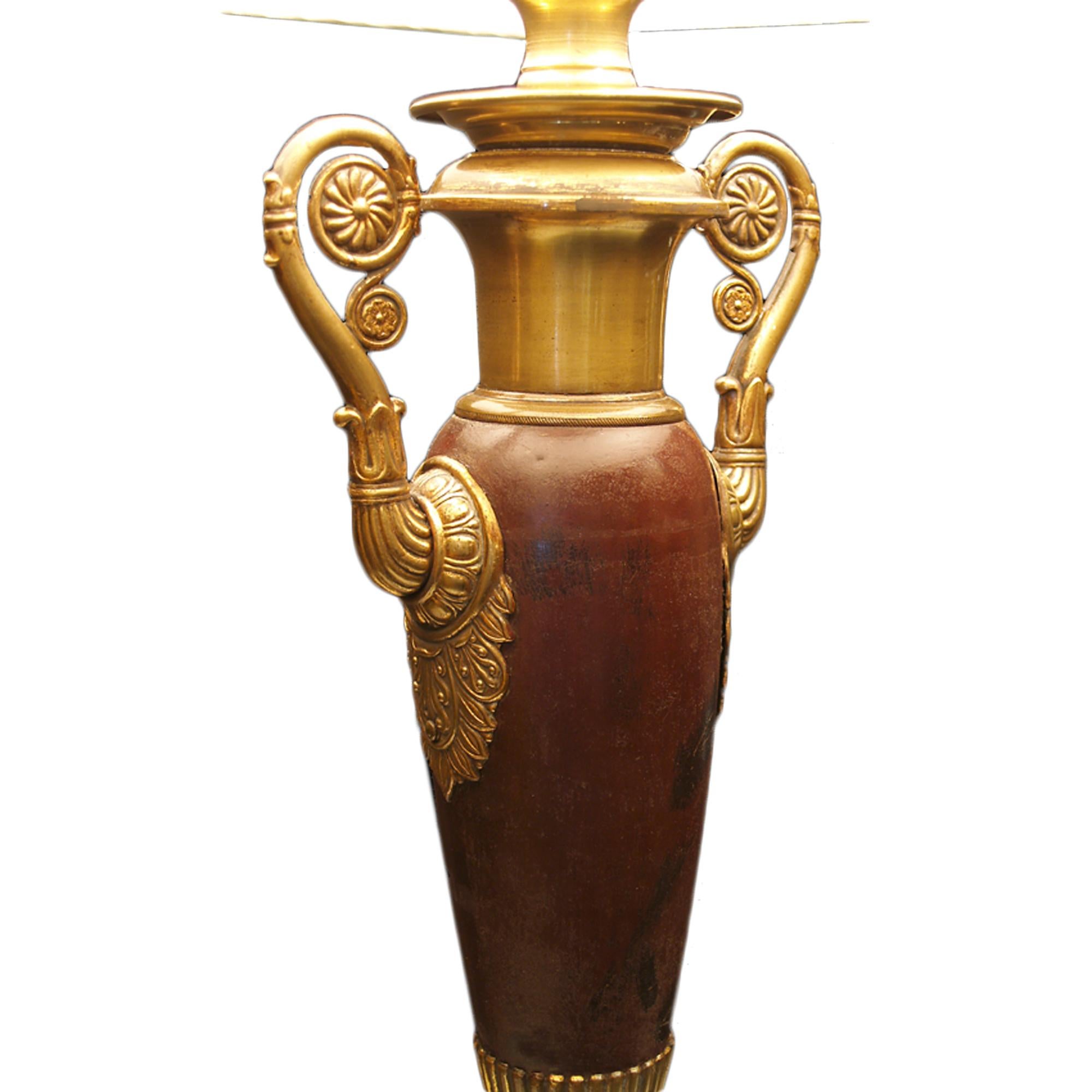 A very attractive 19th century Neo-Classical st. metal lamp with a patinated bronze finish. The lamp is raised on a square base with a bronze color border of acanthus leaves. Above is the urn shape on gilt metal reeded pedestal with scrolled gilt