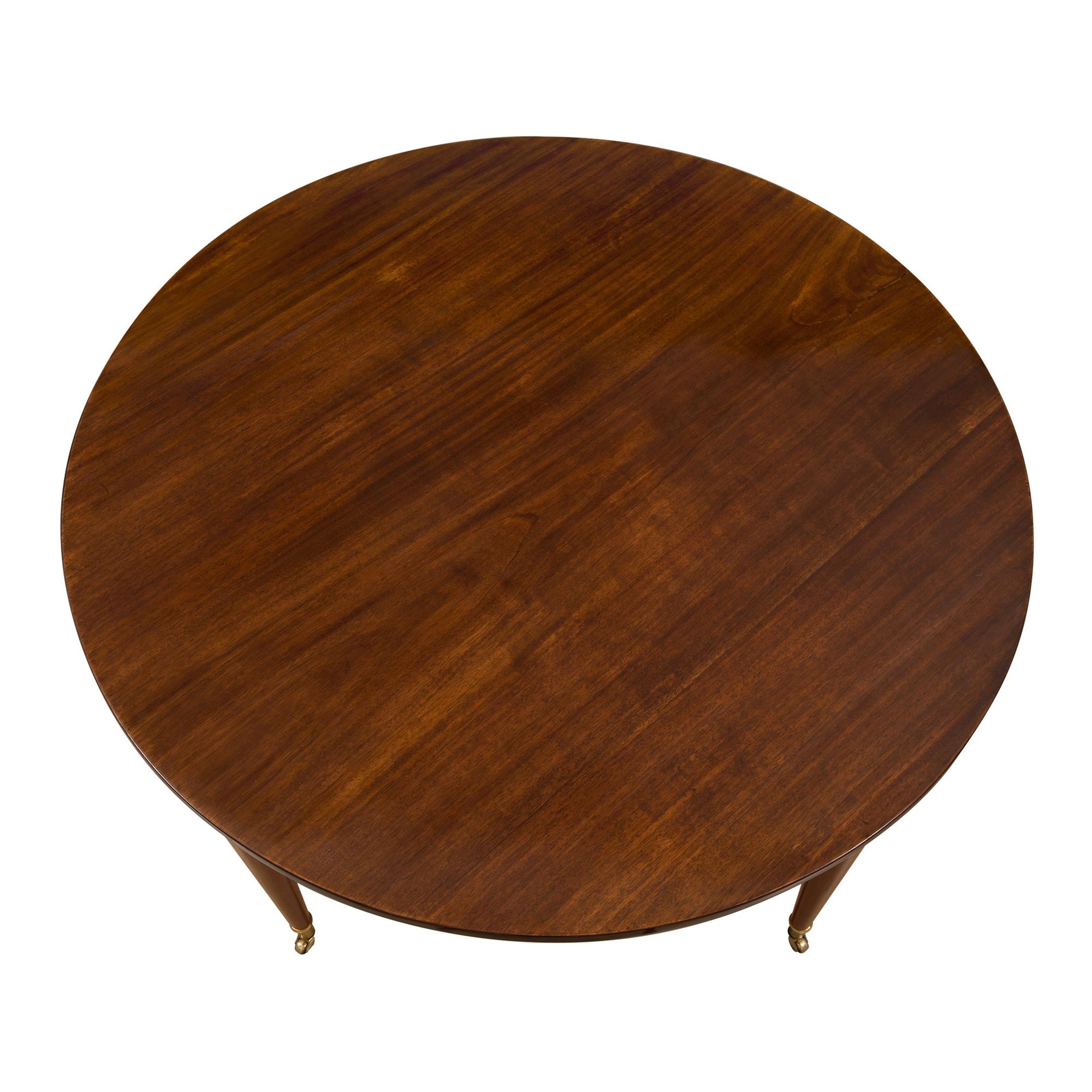 Une très élégante table centrale en acajou de style néo-classique français du 19ème siècle. La table est surélevée par de fins pieds circulaires fuselés avec sabots en bronze doré et leurs roulettes d'origine. Au-dessus de chaque pied se trouvent de
