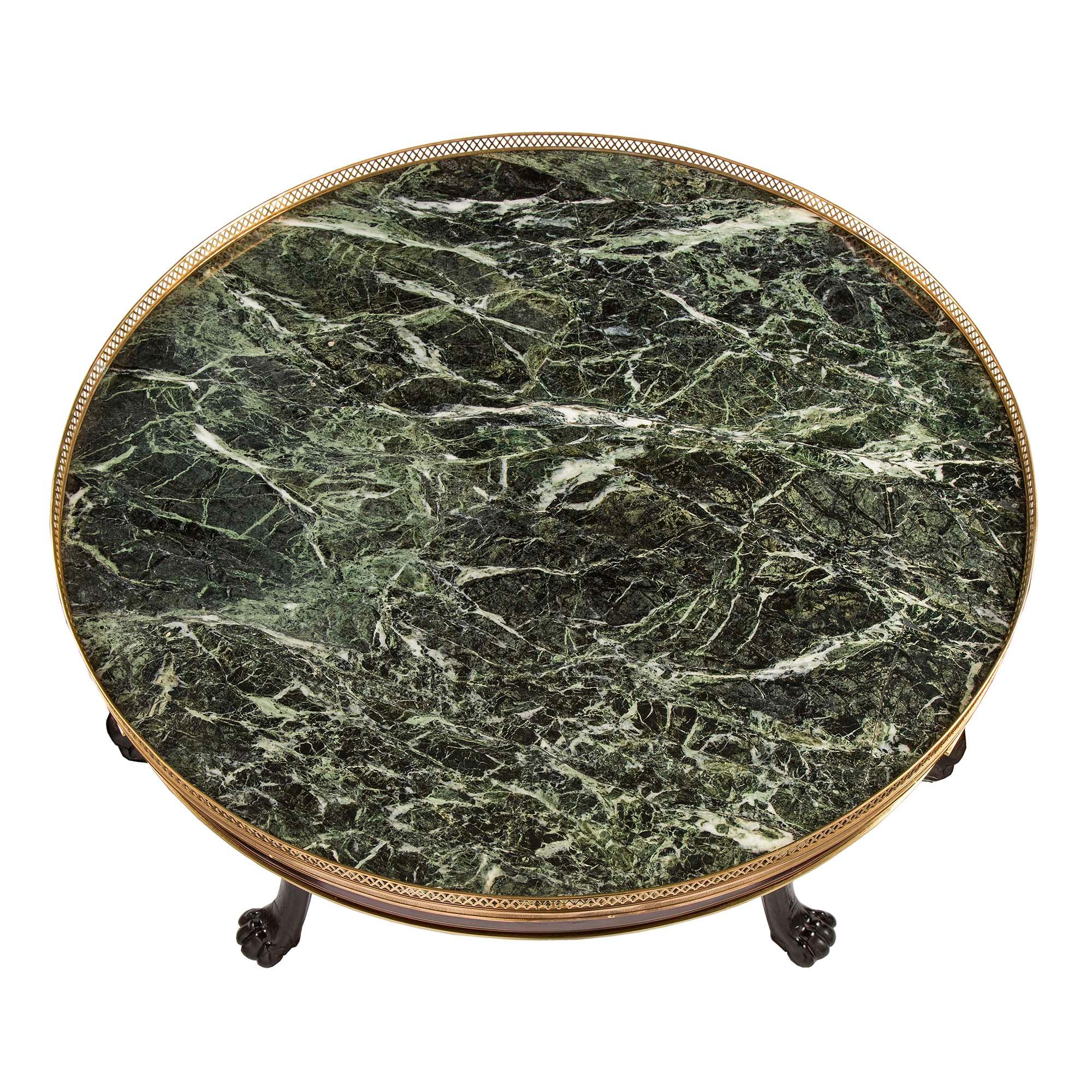Très belle table centrale néo-classique française du XIXe siècle en acajou, marbre et bronze doré. La table est surélevée par trois remarquables supports en bois fruitier ébonisé avec des pieds en forme de pattes et des visages d'oiseaux richement