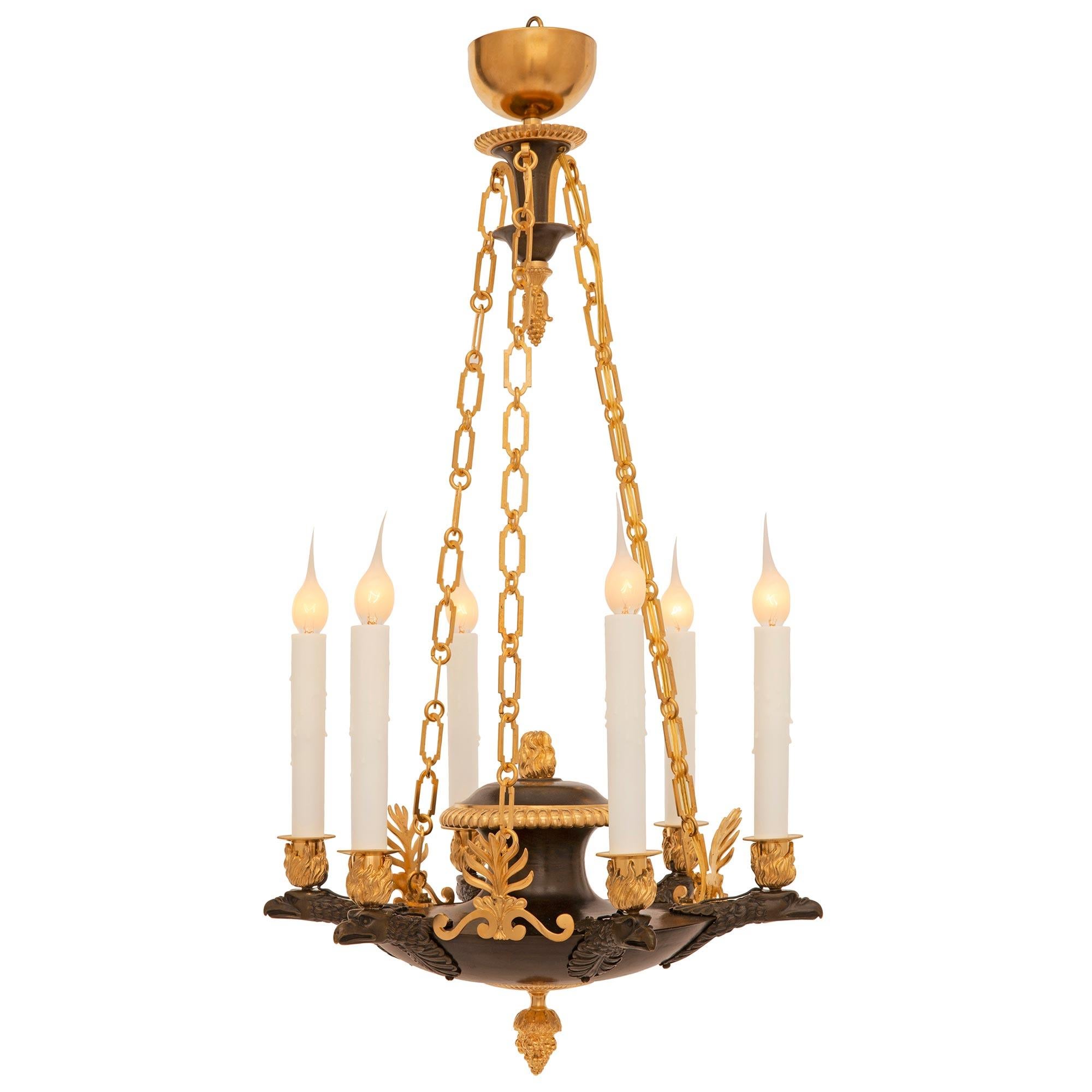 Un lustre néo-classique français du 19ème siècle en bronze patiné et bronze doré. Le lustre à six bras est centré par un magnifique épi de faîtage en bronze doré richement ciselé sous l'élégant corps arrondi avec des palmettes finement détaillées et