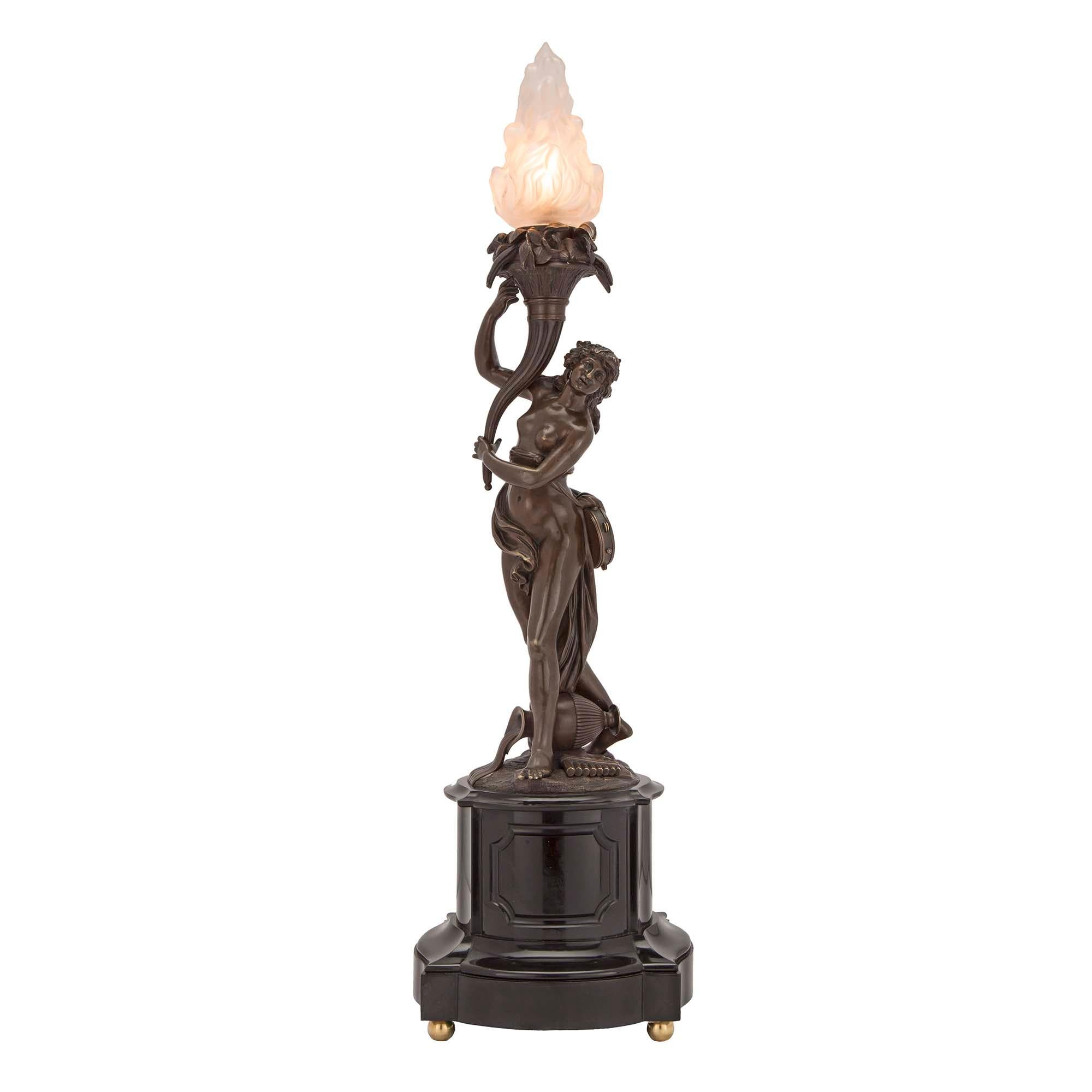 A handsome and most elegant true pair of French 19th century Neo-Classical patinated bronze and black Belgian marble lamps. Each lamp is raised by a square mottled marble base with convex sides and a decorative carved recessed center. Above are