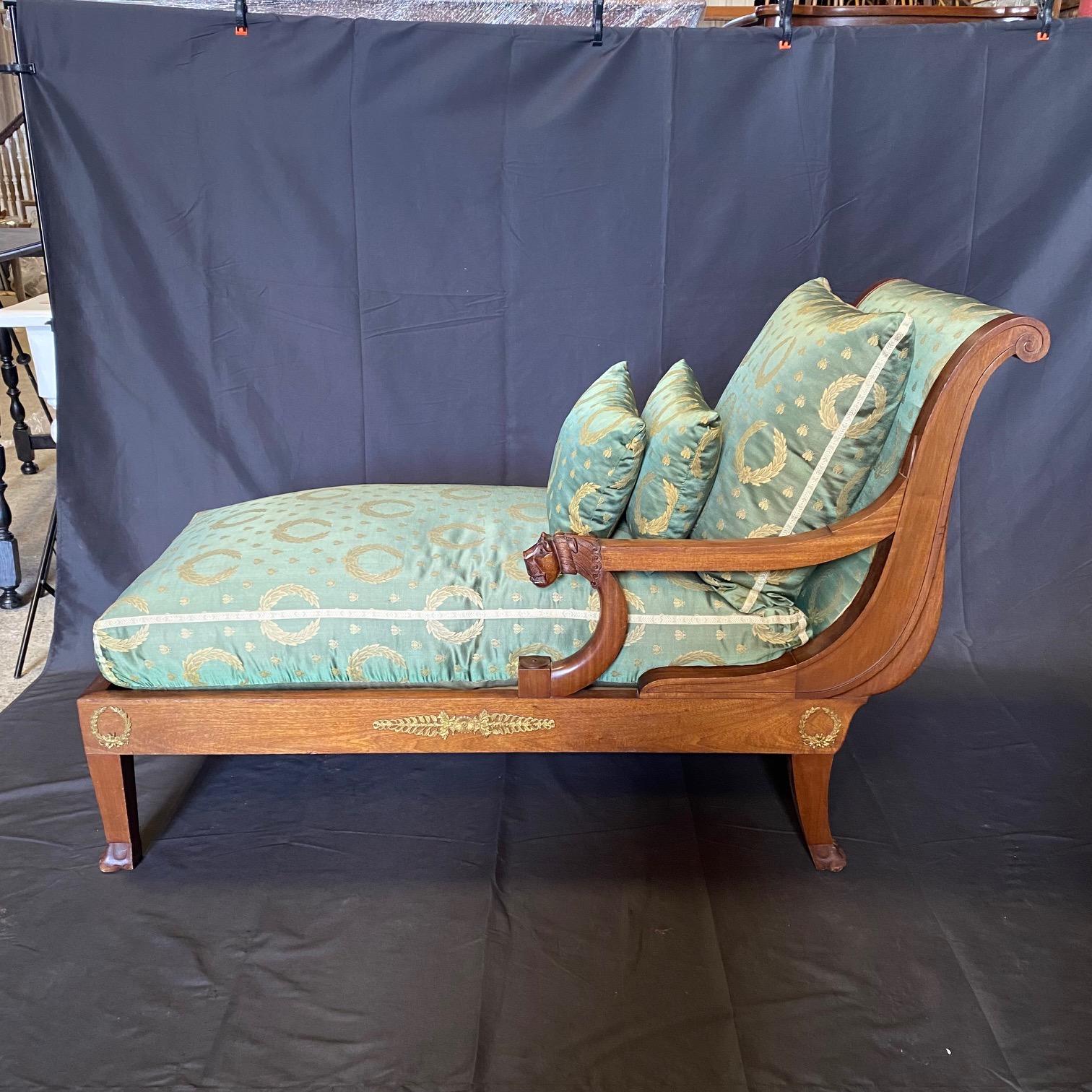 An extremely elegant French 19th-century Neoclassical mahogany upholstered rcamier. The chaise lounge has a stunning carved lion head armrest, and lovely neoclassical green silk wreath upholstery, and is supported by lovely lightly tapered fluted