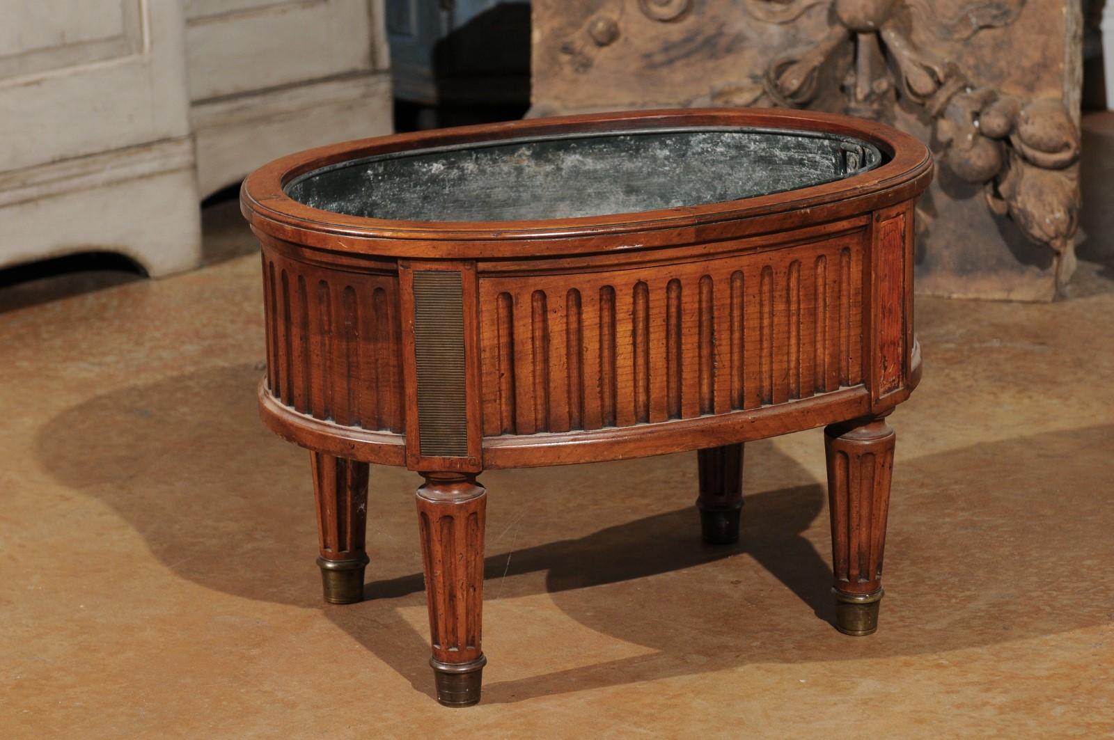 A French neoclassical style cherry jardinière planter from the 19th century, with tin-lined interior, fluted motifs and tapering legs. Born in France during the 19th century, this handsome jardinière, made of cherry, features an oval-shaped