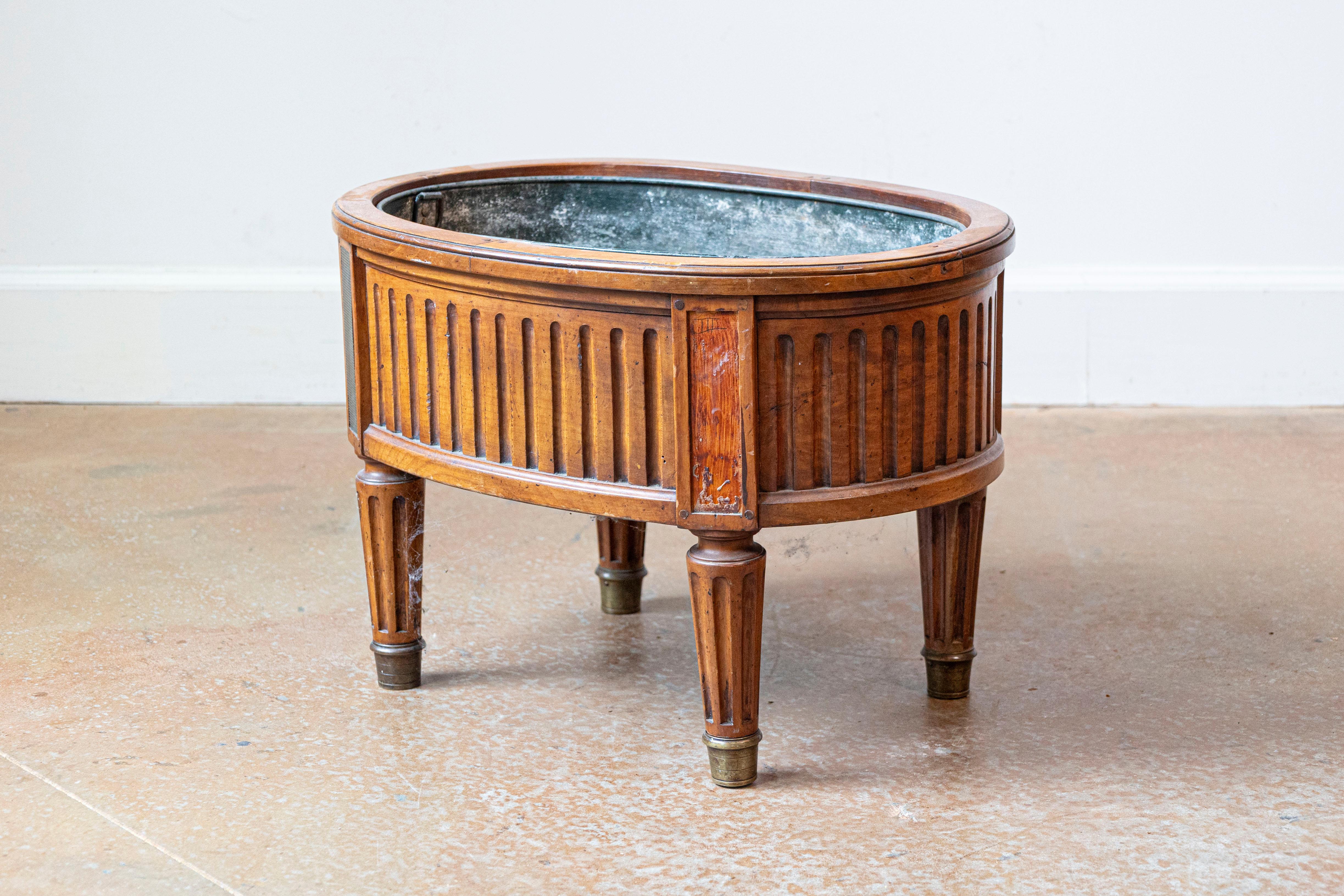 A French neoclassical style cherry jardinière planter from the 19th century, with tin-lined interior, fluted motifs and tapering legs. Born in France during the 19th century, this handsome jardinière, made of cherry, features an oval-shaped
