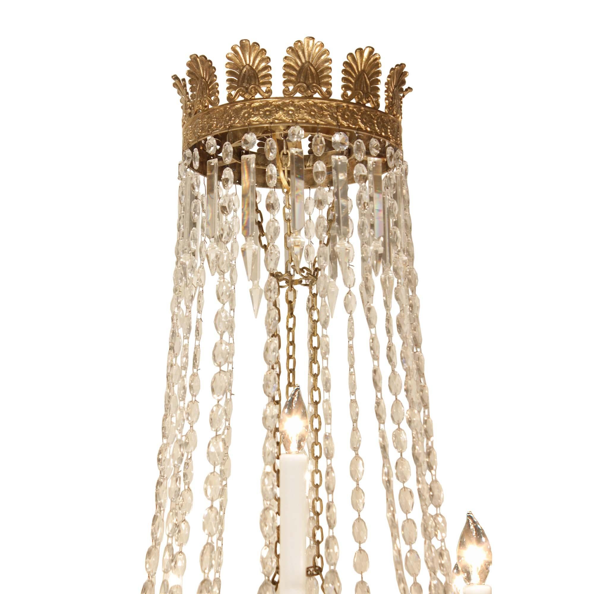 A stunning French 19th century neo-classical st. crystal and ormolu chandelier. At the base of the chandelier are eight descending circular ormolu bands of impressive hanging crystals and a central ormolu acorn finial at the bottom. Above are the