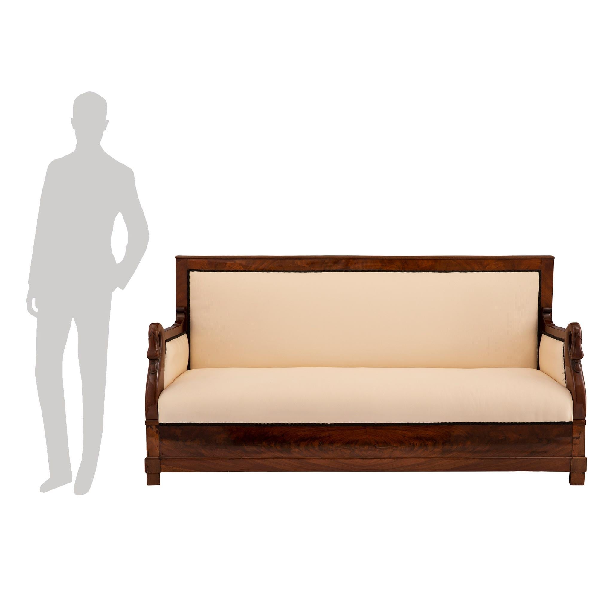 Ein schönes französisches neoklassizistisches Sofa aus dem 19. Kubanisches Mahagoni-Sofa. Das Sofa steht auf feinen, quadratischen Beinen unter dem geraden, schmetterlingsfurnierten Fries, der die schöne Mahagonimaserung zur Geltung bringt. Jeder