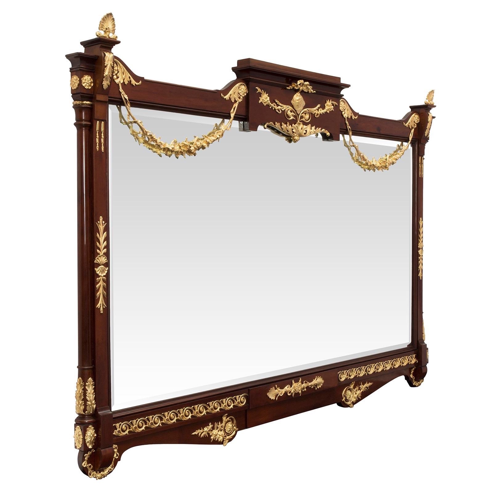 A stunning pair of French 19th century neo-classical st. mahogany and ormolu mirrors. The original beveled mirror plates are framed within a striking and most decorative mahogany border. The scalloped shaped base displays richly chased scrolled and