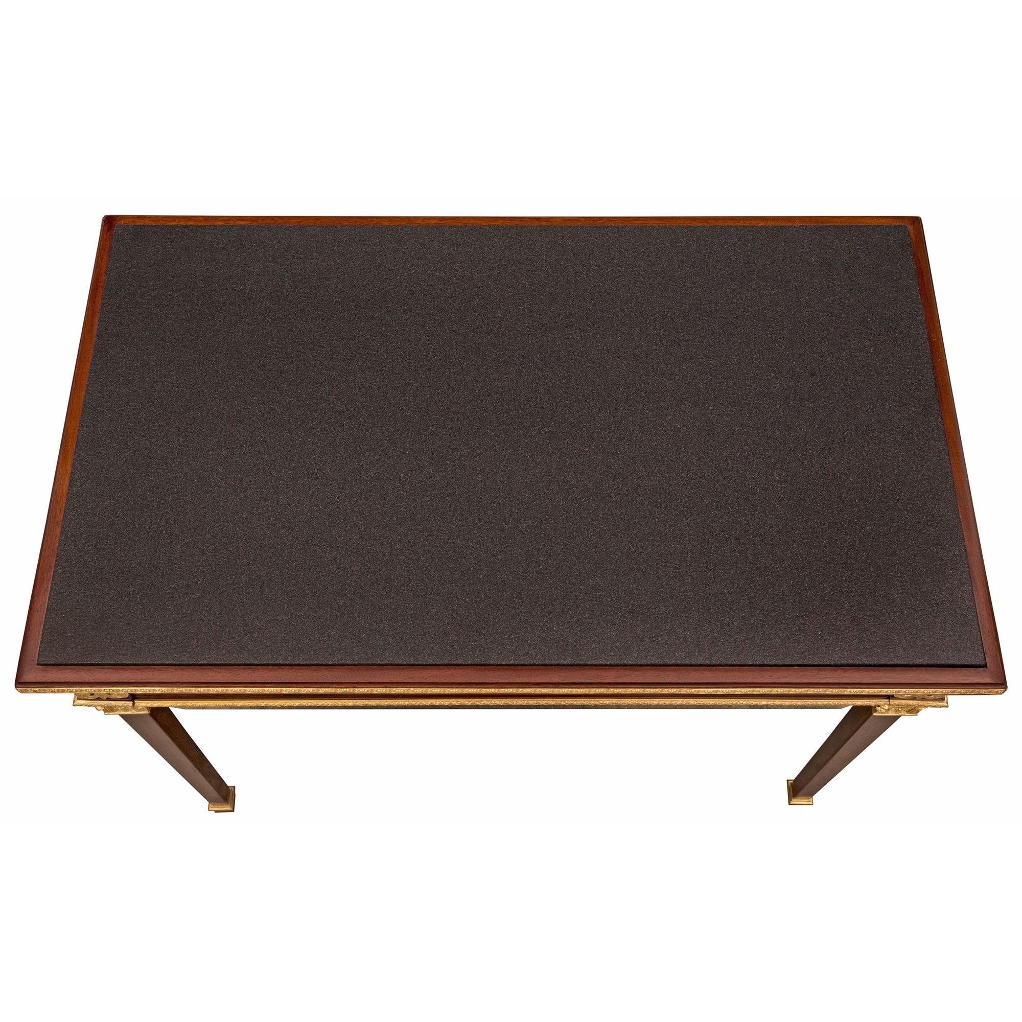 Un sorprendente tavolino/scrivania in stile neoclassico francese del XIX secolo in mogano, ormolu e ardesia. Il tavolo è sollevato da eleganti gambe quadrate affusolate con sabot in ormolu screziato e capitelli foliati riccamente cesellati. Sopra