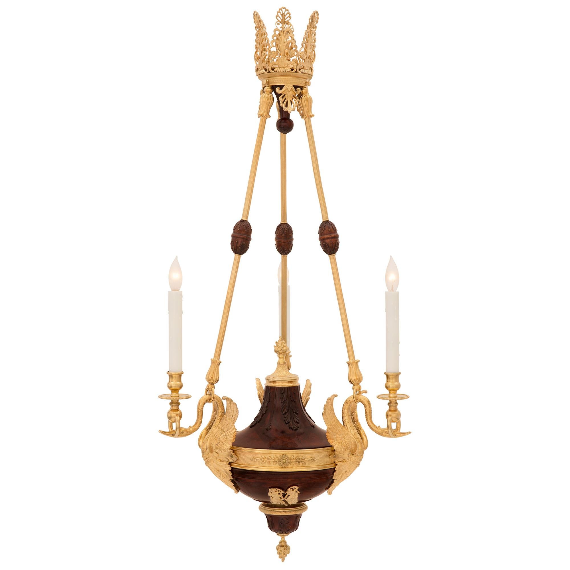 An exceptional French 19th century Neo-Classical st. maple and ormolu chandelier. The chandelier is centered by a fine bottom inverted finial of the eternal flame amidst carved maple acanthus leaves and an elegant wrap around ormolu band. At the