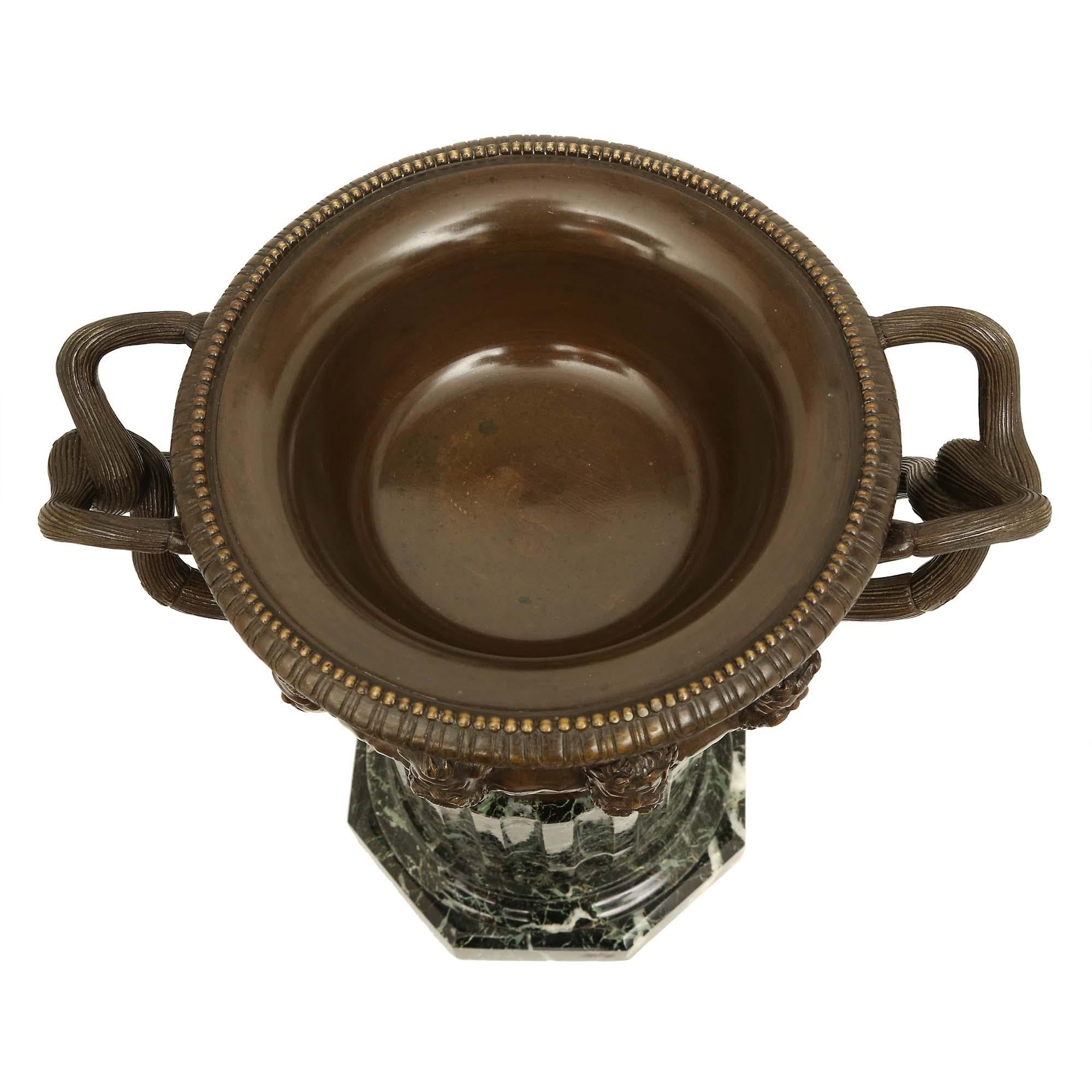 Bella tazza in bronzo patinato neoclassico francese del XIX secolo. L'urna è sollevata su una base esagonale in marmo Vert de Patricia sotto il supporto di una colonna scanalata con socle in bronzo patinato. L'imponente tazza in bronzo patinato ha