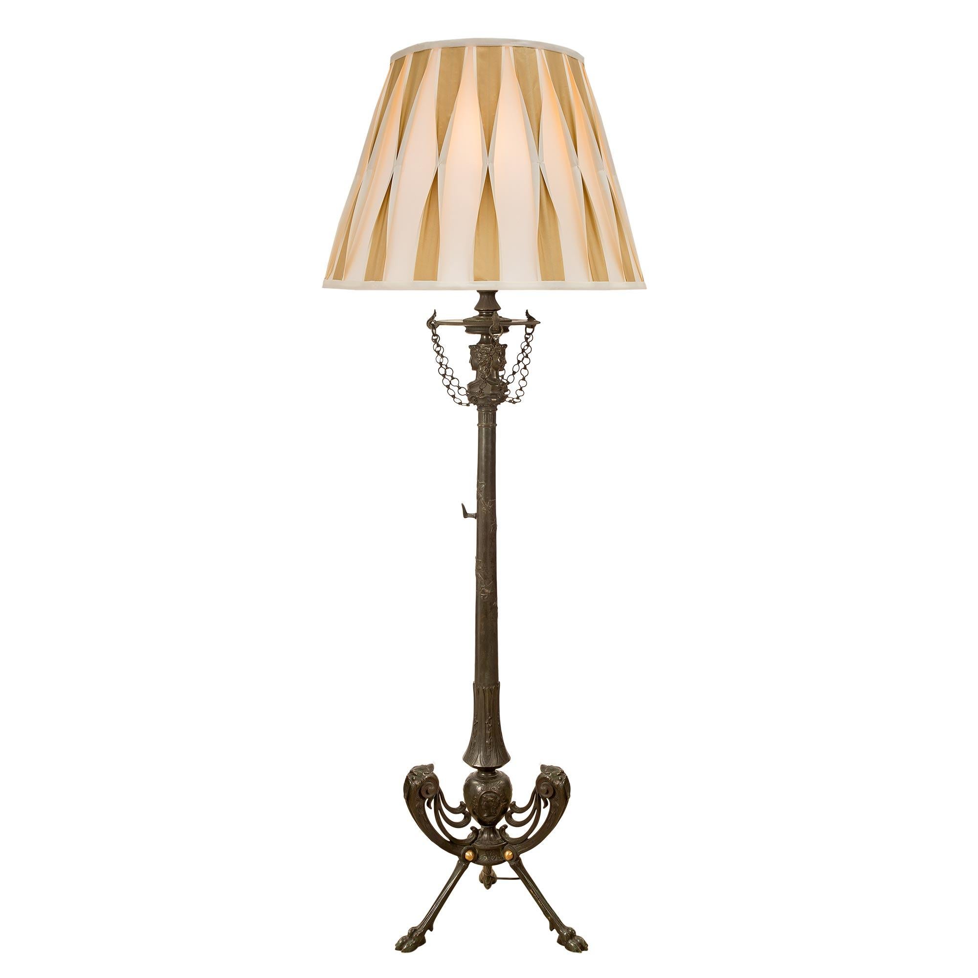 Exceptionnel lampadaire néoclassique français du XIXe siècle en bronze vert-de-gris et bronze doré. La lampe repose sur trois beaux pieds en patte d'oie richement ciselés et sur des supports à volutes percées avec de fines têtes de lion et des