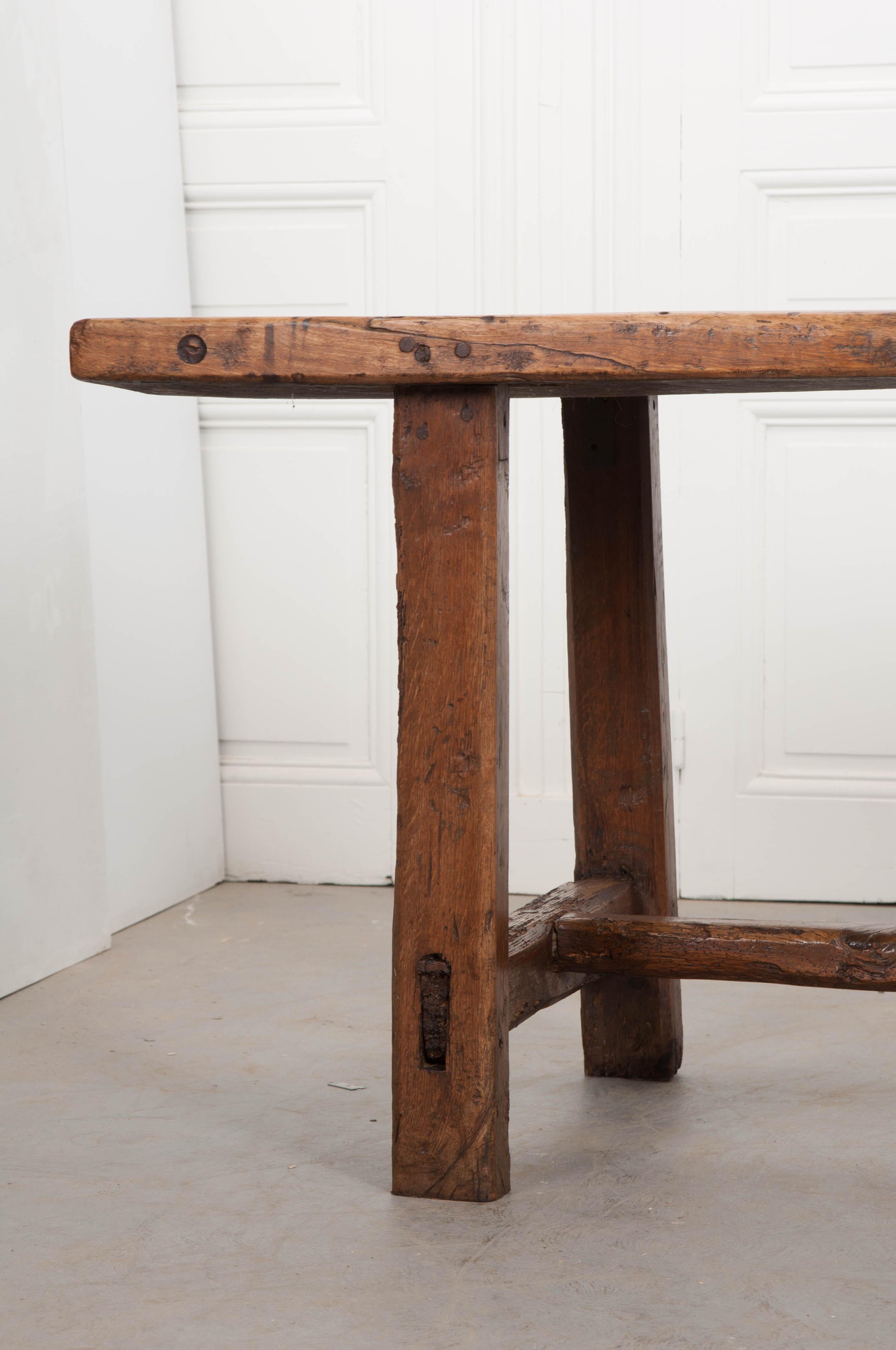 This stunning and incredibly well-made French farmhouse table, circa 1860s, was created out of oak and walnut using Classic dowel joints and mortise and tenon. The hefty two-inch plank top boasts a gorgeous, rich patina and is made of an oak panel