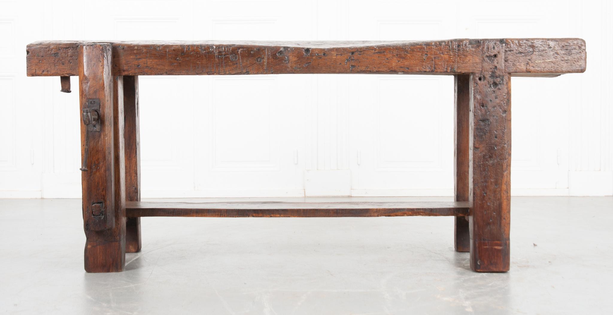 This French 19th century workbench is made of solid oak with a wonderful patina throughout. The top is made from a single board 4-½” thick! Two dowel holes in the top and a vise grip in working condition make this antique a functional workbench. A