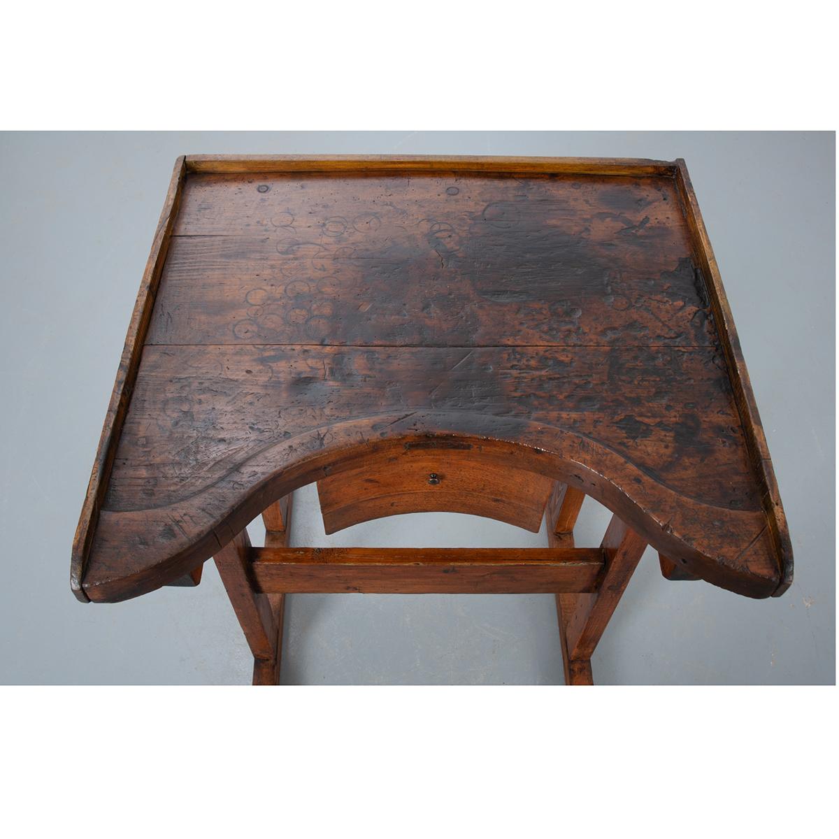 This specialized oak desk was made in France.  Used by jewelers, the desk’s lifted surface brings the table towards the artist, minimizing reach, and saving their aching backs.  The work surface has a three quarter wood gallery and raised surface