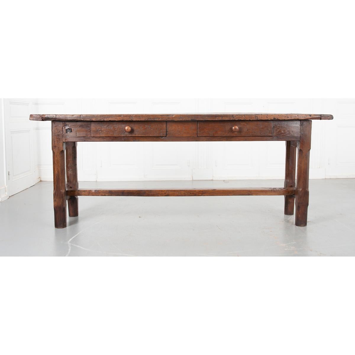 This primitive oak console has a gorgeous patia that shows off the rich color and age of the wood. Sitting upon a rectangular apron with two nice-sized front drawers, fitted with turned wooden pulls. The whole is supported by sturdy carved fluted
