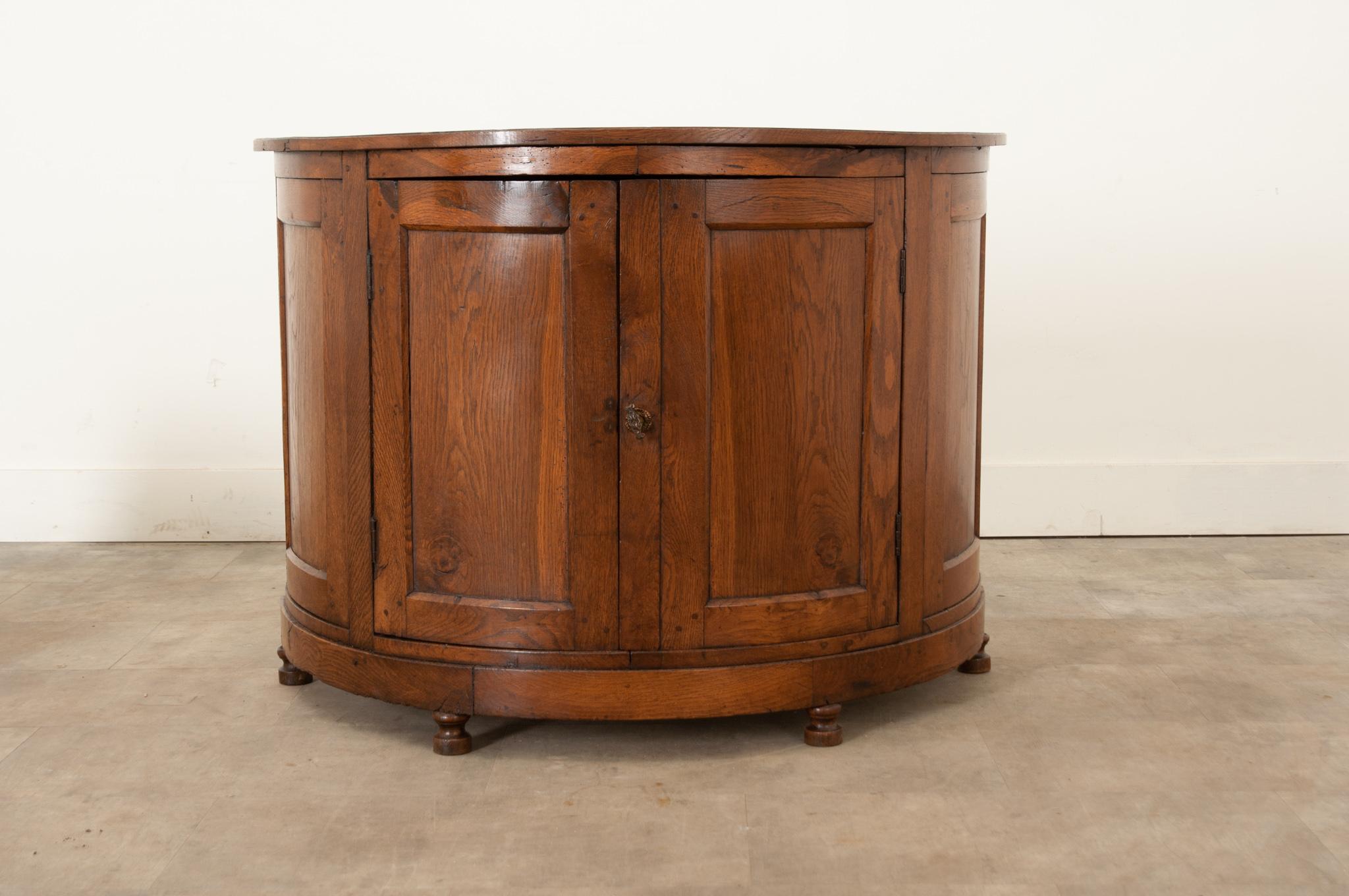 A 19th century solid oak buffet, made in France circa 1830. This piece is Demilune in shape, giving it a distinct, finished presence. Constructed of beautifully aged oak, two centre doors are hung on metal hinges and retain their original inside