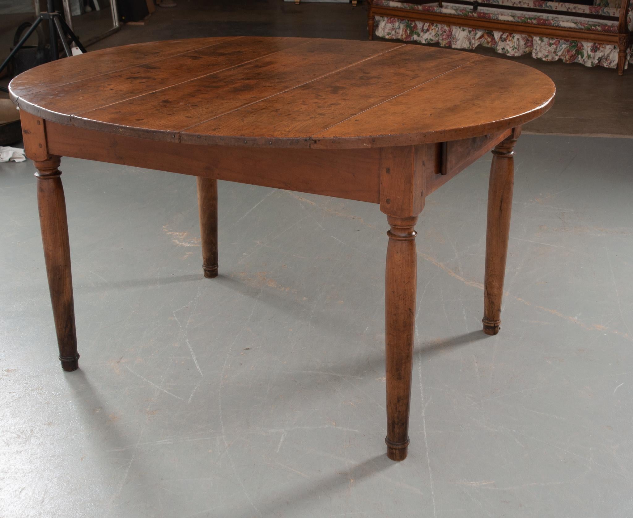 An incredibly charming solid walnut dining room table from 19th century France! The wood is fabulously patinated with many marks of past lives lived. A sizable apron houses a single drawer fixed with a simple turned pull. Opening the drawer reveals