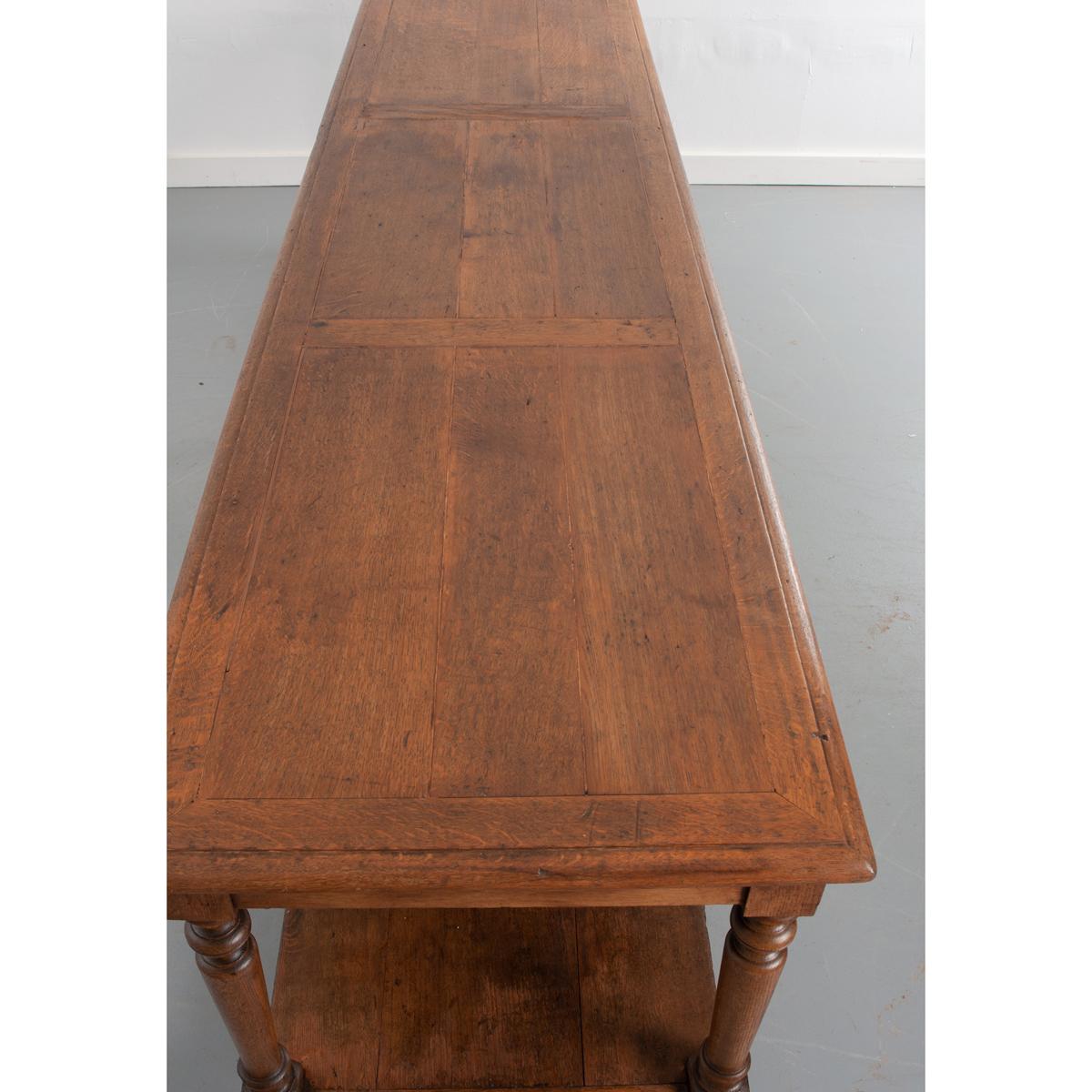 This monumental oak drapery table is from France and is over nine and a half feet long! The surface is divided into three sections with a border around each, all constructed of beautiful, rich oak planks. This large top rests upon an apron and eight