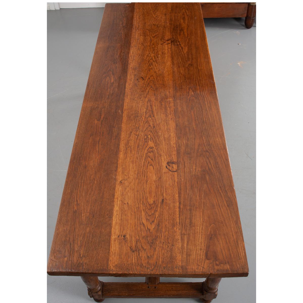 This handsome oak table features a three plank solid top. A simple apron is outfitted with a single, deep drawer with a turned wood knob. The whole rests on four turned legs connected with a H-form stretcher. The hand pegged, treenail construction