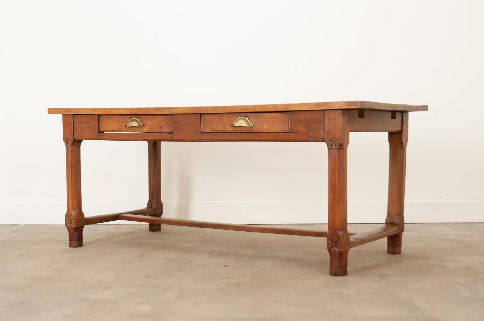 This solid oak farm table from France is full of rustic charm. Long planks of oak make up the smooth rectangular top and showcase a beautiful patina. The apron houses two drawers that open easily with brass crescent pulls. The interior of one drawer