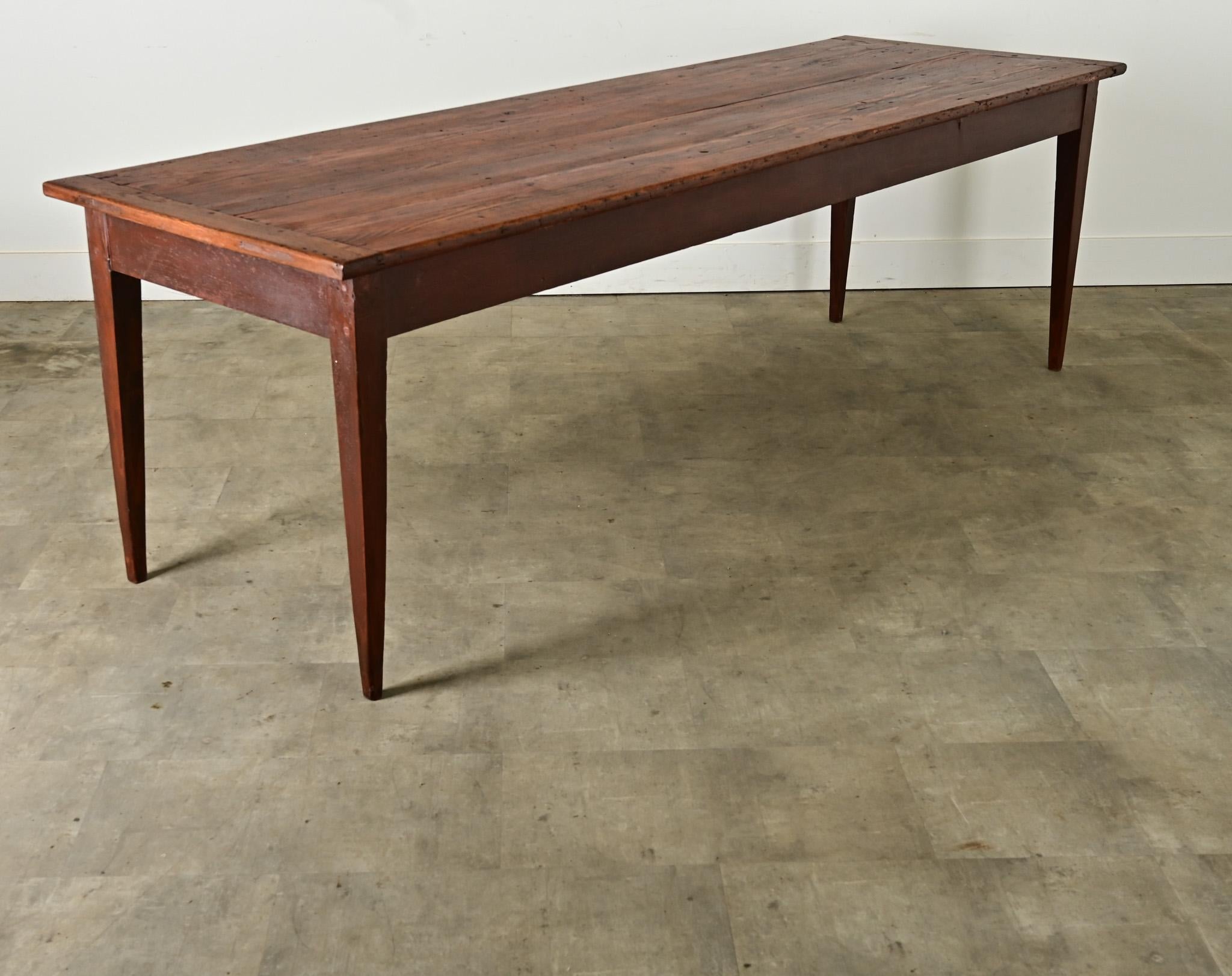 This rustic farmhouse dining table from 19th century France will easily accommodate 8- 10 guests. The simple plank top, assembled by tongue-and-groove joinery, has many layers of patina with breadboard ends over a study base. The long and narrow