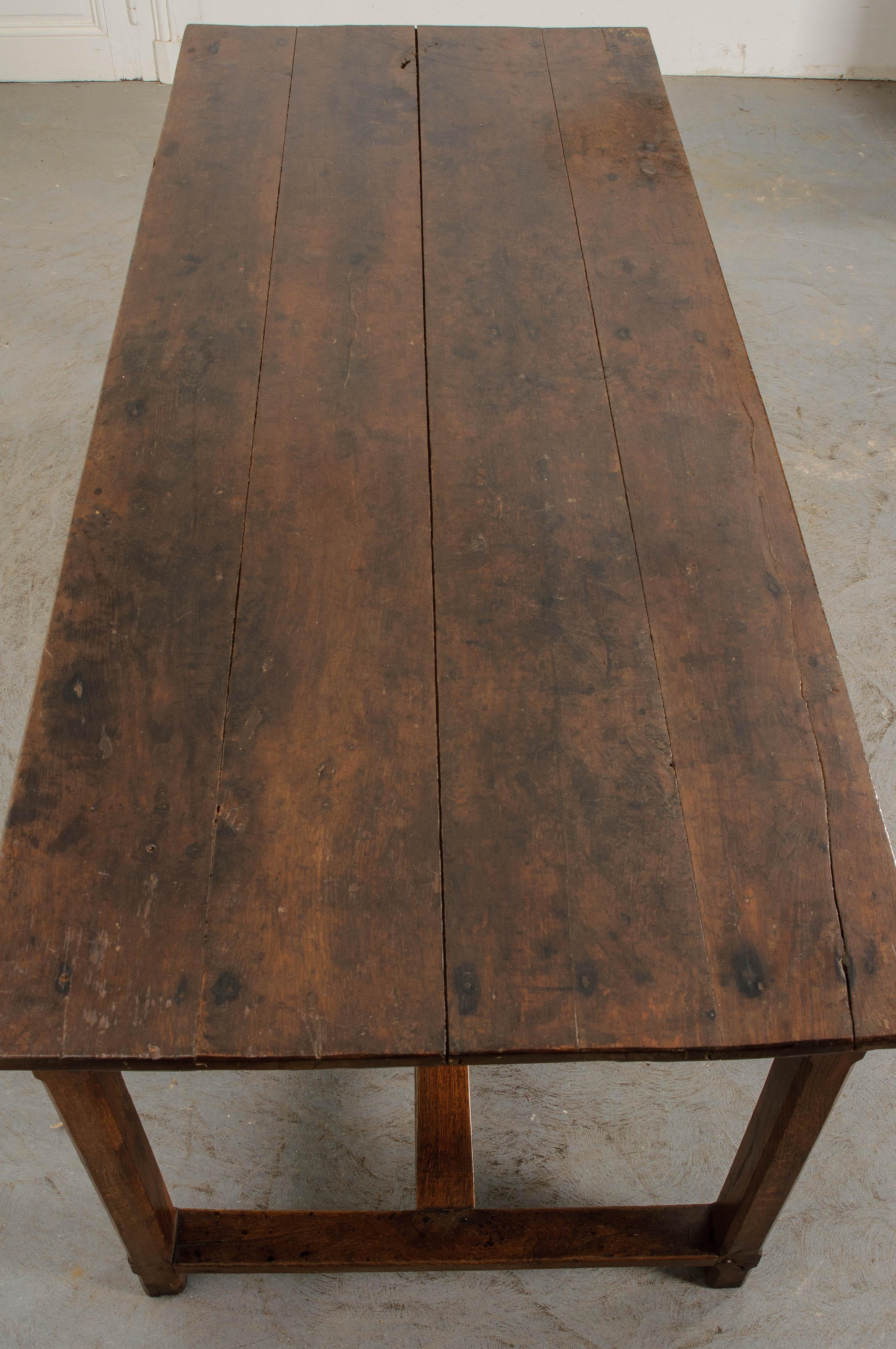 This fine 19th century solid-oak table, constructed using impeccable peg joinery, has a rich, deep finish that has gained a beautiful patina over time. The oak is darker in color. The tongue-and-groove plank top is set over an apron which