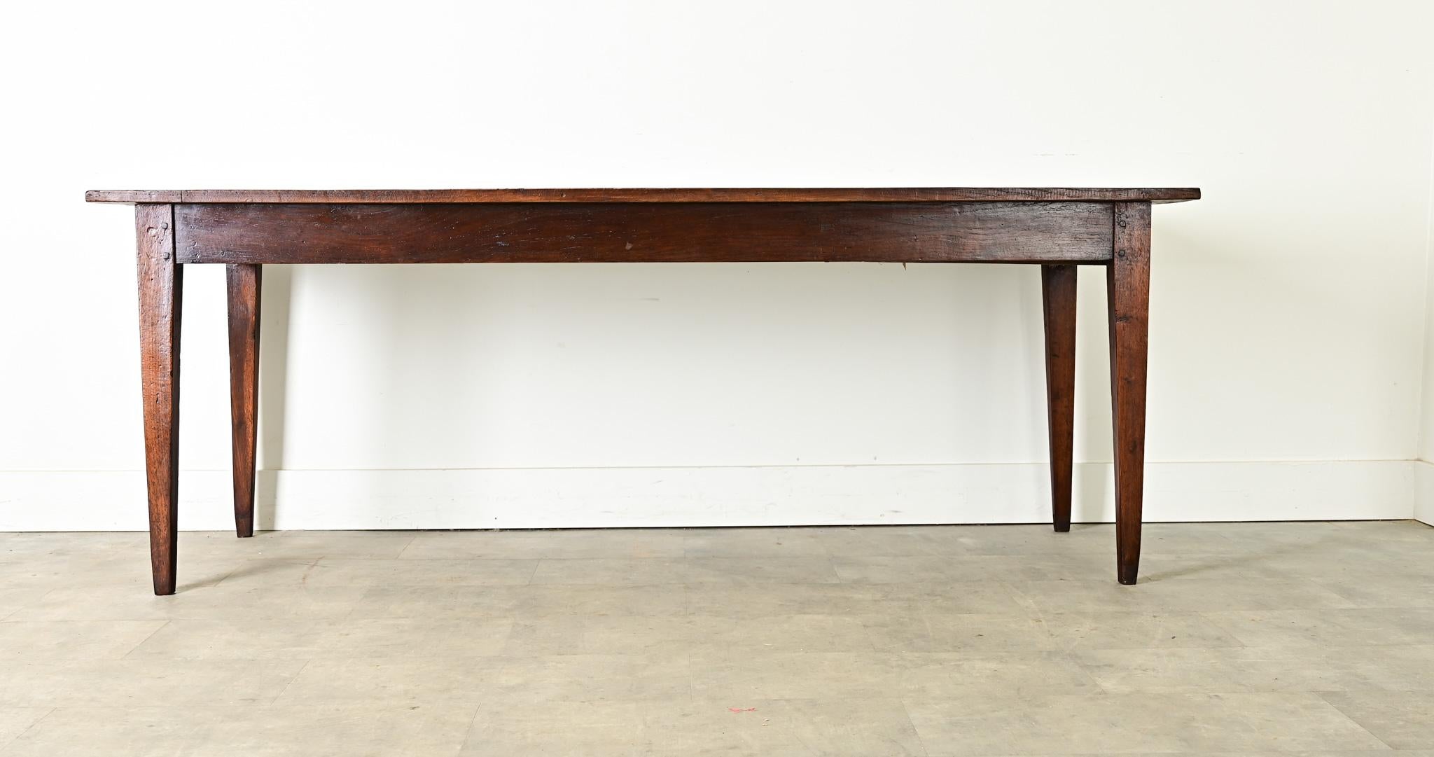 Magnifique table de salle à manger de ferme du XIXe siècle en France, fabriquée à la main en chêne. Les planches supérieures présentent un grain ondulé parsemé de têtes de chevilles carrées sous le ton café foncé et la patine légèrement gravée. Le