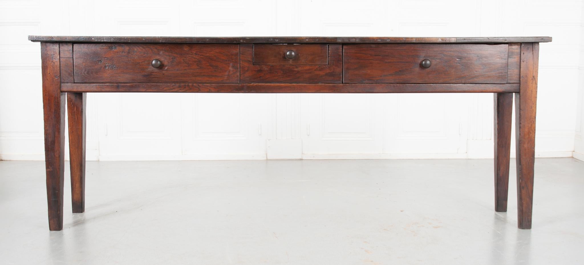 This provincial low table has a beautiful patina top, made from two planks of solid oak nailed together to form a narrow surface. Housed in the apron are three drawers of two different sizes all fitted with turned wooden pulls, offering plenty of
