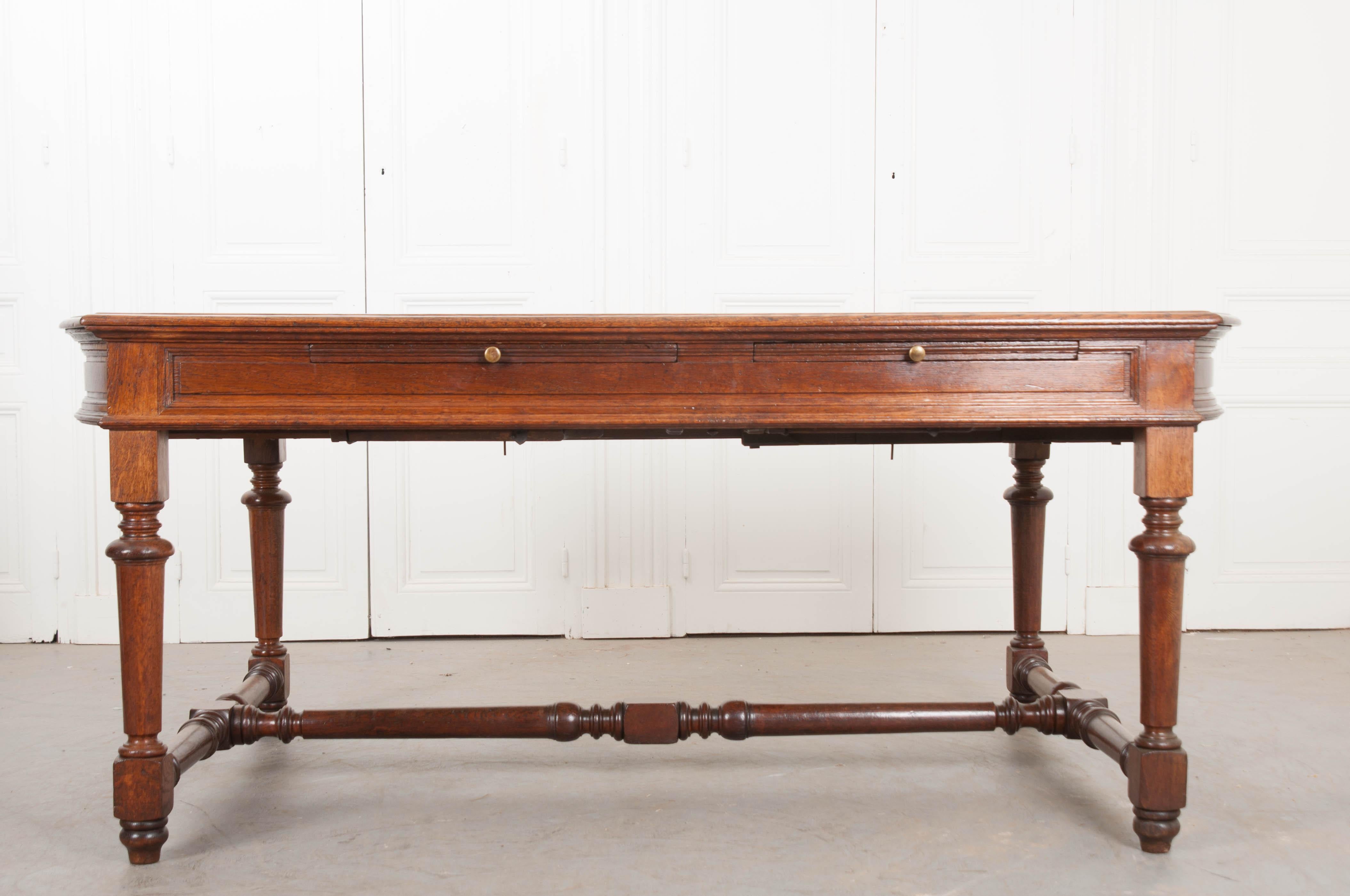 This fantastic oak sewing table is from France, circa 1860. Large enough for two people sitting next to each other, one side features a pair of slide-out surfaces, each outfitted with carved compartments for scissors and a duster. There is also a