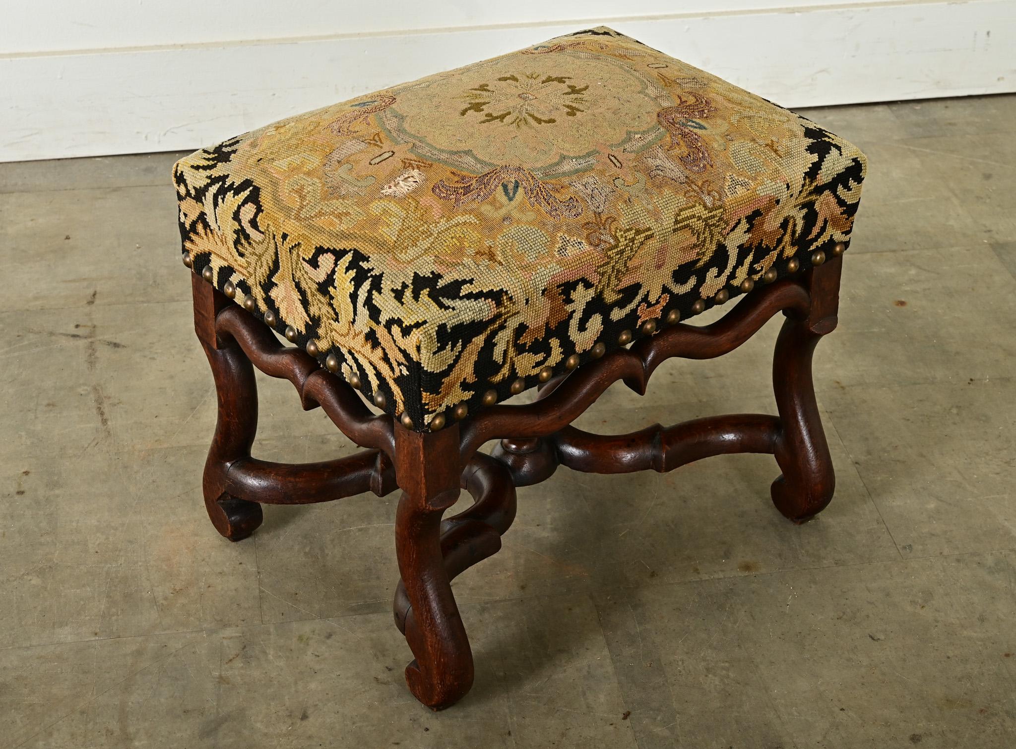 Outstanding French 19th century Louis XIV style bench (or footstool) with needlepoint upholstery, raised on four Os de Mouton legs with stretcher, entirely hand-carved from walnut. The tapestry-like seat features a dense pattern of radiating, leafy