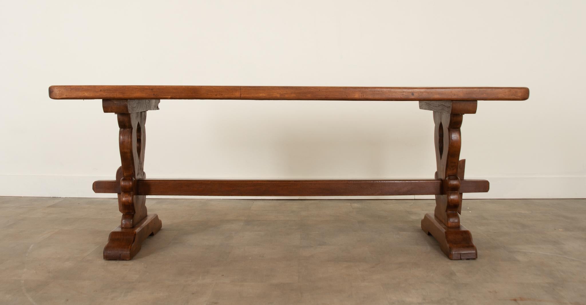This French solid oak trestle base table is perfect for your casual dining experience. The 2-1/4” thick top is the perfect scale over its shaped and pierced base. The long stretcher in the center of the bases adds support and contributes the over