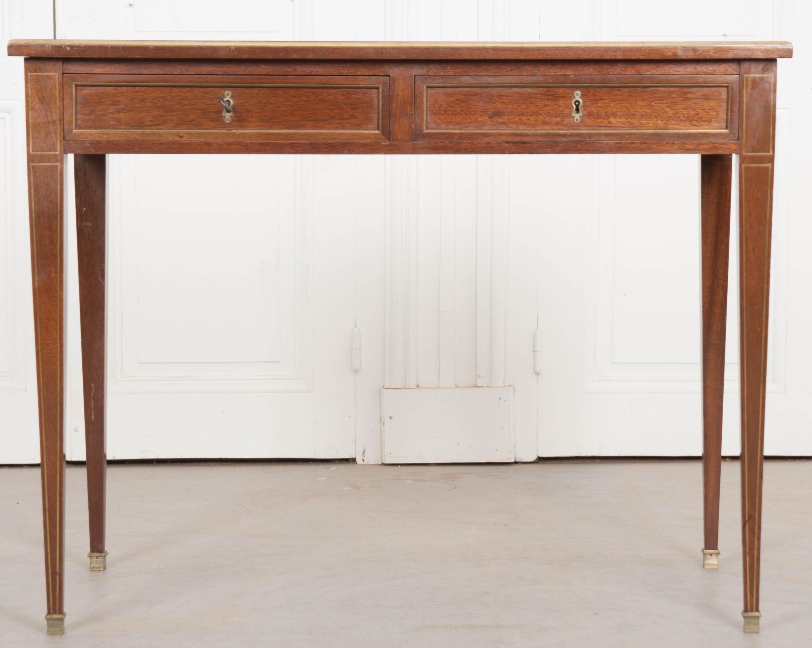 This petite French 19th century writing desk made of oak has a very unique, worn leather writing surface. The previous owners of this lovely little desk made a few ‘honest’ repairs using square clippings of leather with gilt crests to cover previous