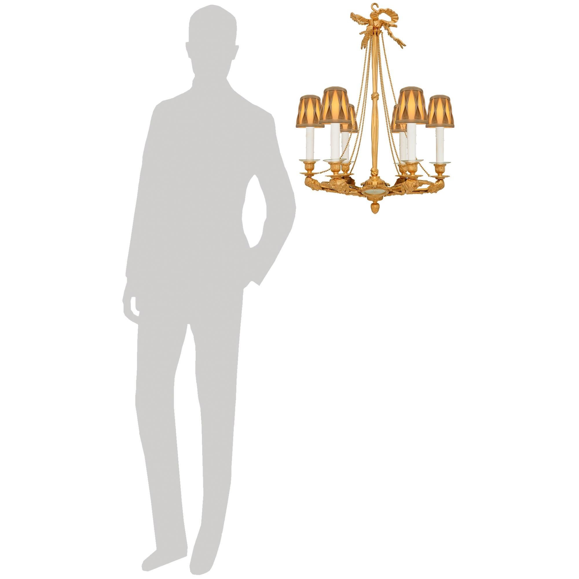 Una singular araña francesa del siglo XIX, de estilo Luis XVI, de ormolu, cristal y porcelana de Wedgwood. Esta elegantísima araña de seis brazos está centrada en la parte inferior por un encantador remate de bellota de Ormolu, antes de que una