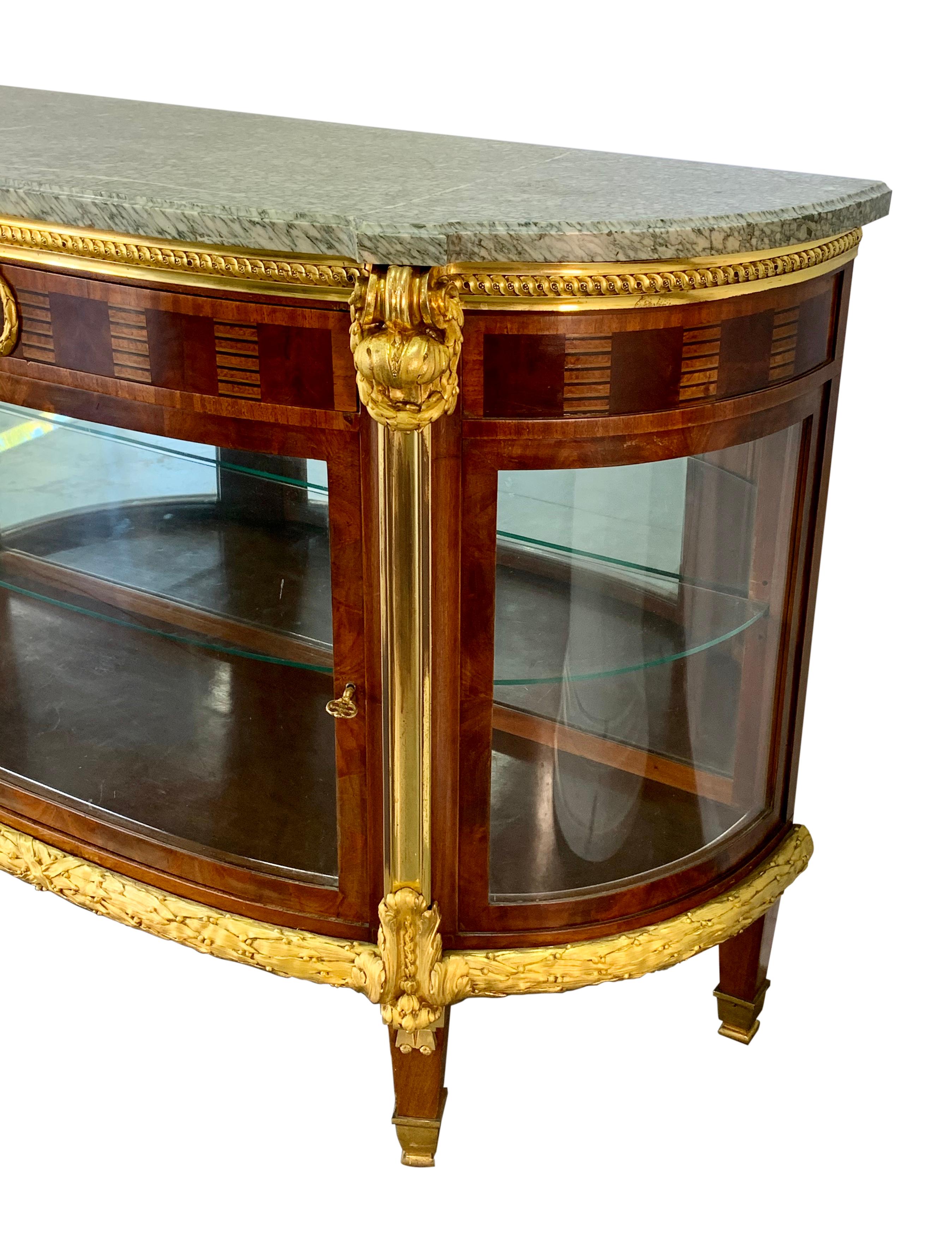 A wonderful quality 19th century French Louis XVI style ormolu mounted commode or vitrine. The D-shaped grey and green veined marble top above a single drawer with parquetry inlays and a central glazed door with high quality gilt bronze