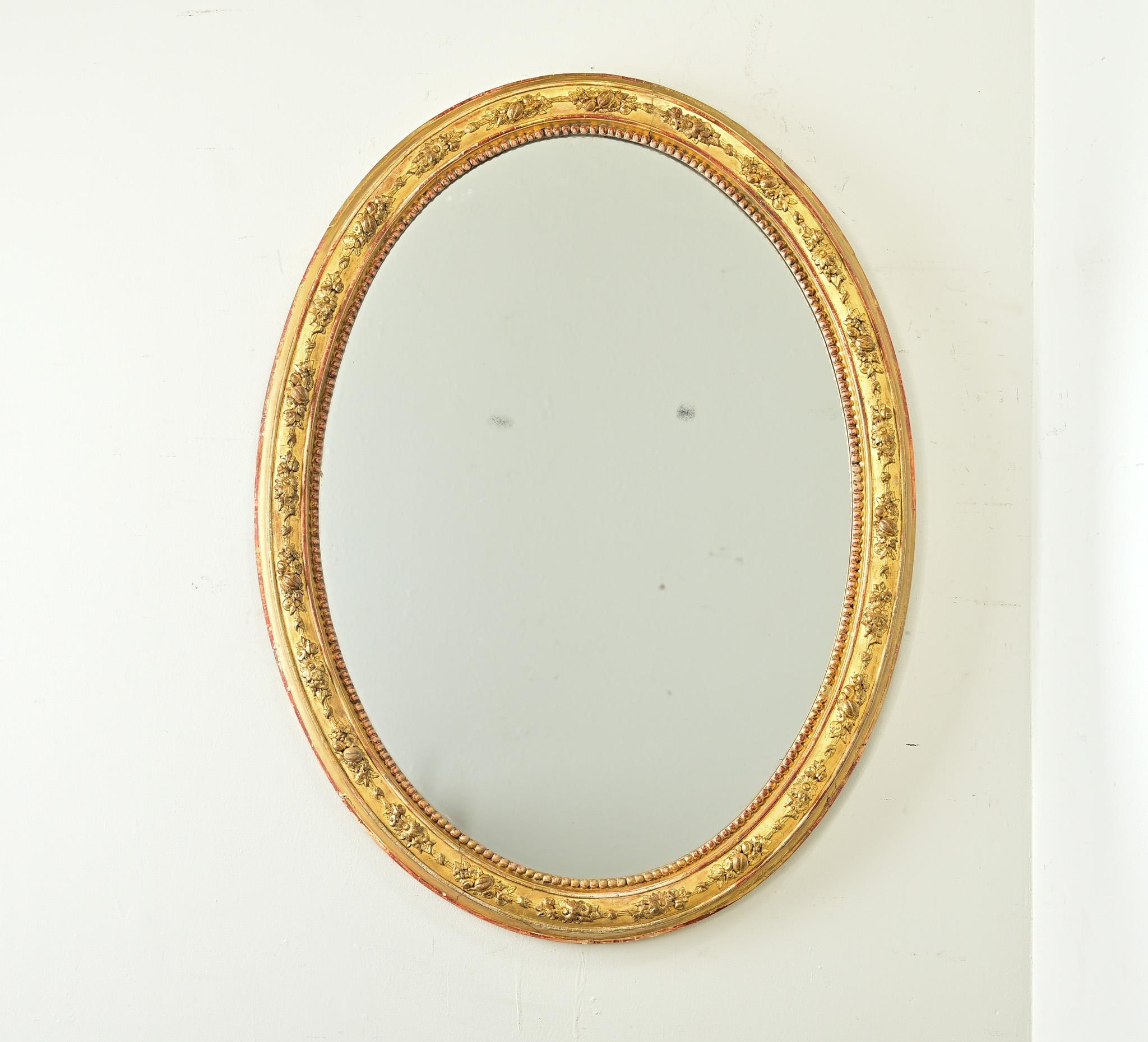 Este impresionante espejo oval dorado con pan de oro data de finales del siglo XIX y simboliza todos los elementos románticos del estilo Luis XVI en forma de pequeños ramilletes colocados alrededor del marco. Los delicados apliques florales están