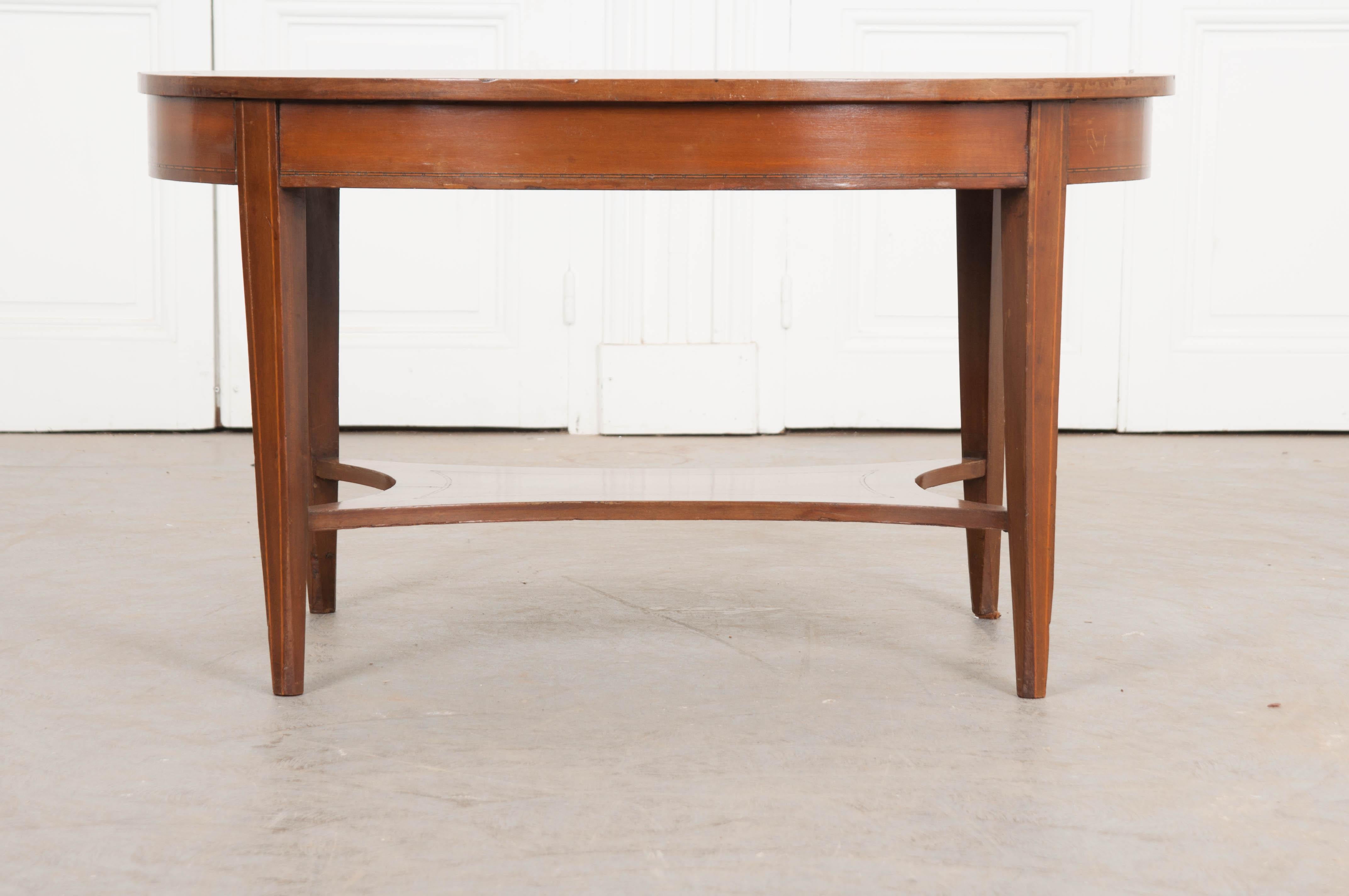 An eye-catching inlay top caps this exceptional mahogany oval coffee table from France. Inspired by the Directoire style, the antique has a subdued elegance that is highly finished while not being ostentatious. A tumbling block motif was inlaid into