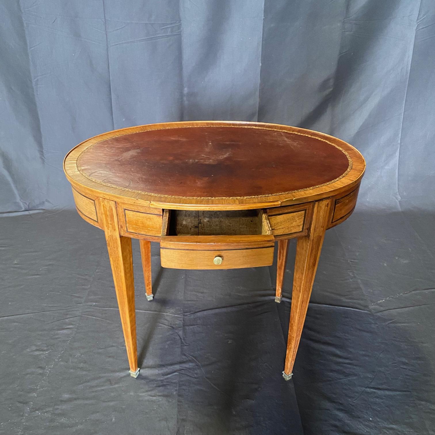 Lovely oval elegant and versatile classic neoclassical side table with beautiful inlay of kingwood and ebony, all topped with a stunning rich leather embossed top. Could be used as a side or accent table or as a petite desk.  Bought in the south of